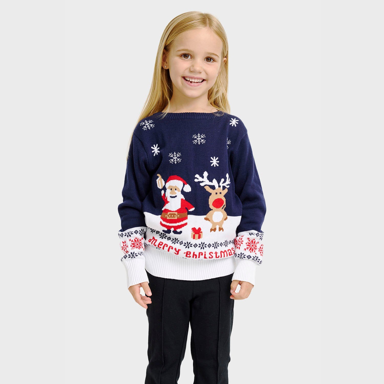 Ett barn vinkar iklädd en vit och blå jultröja med tomten och Rudolf på.