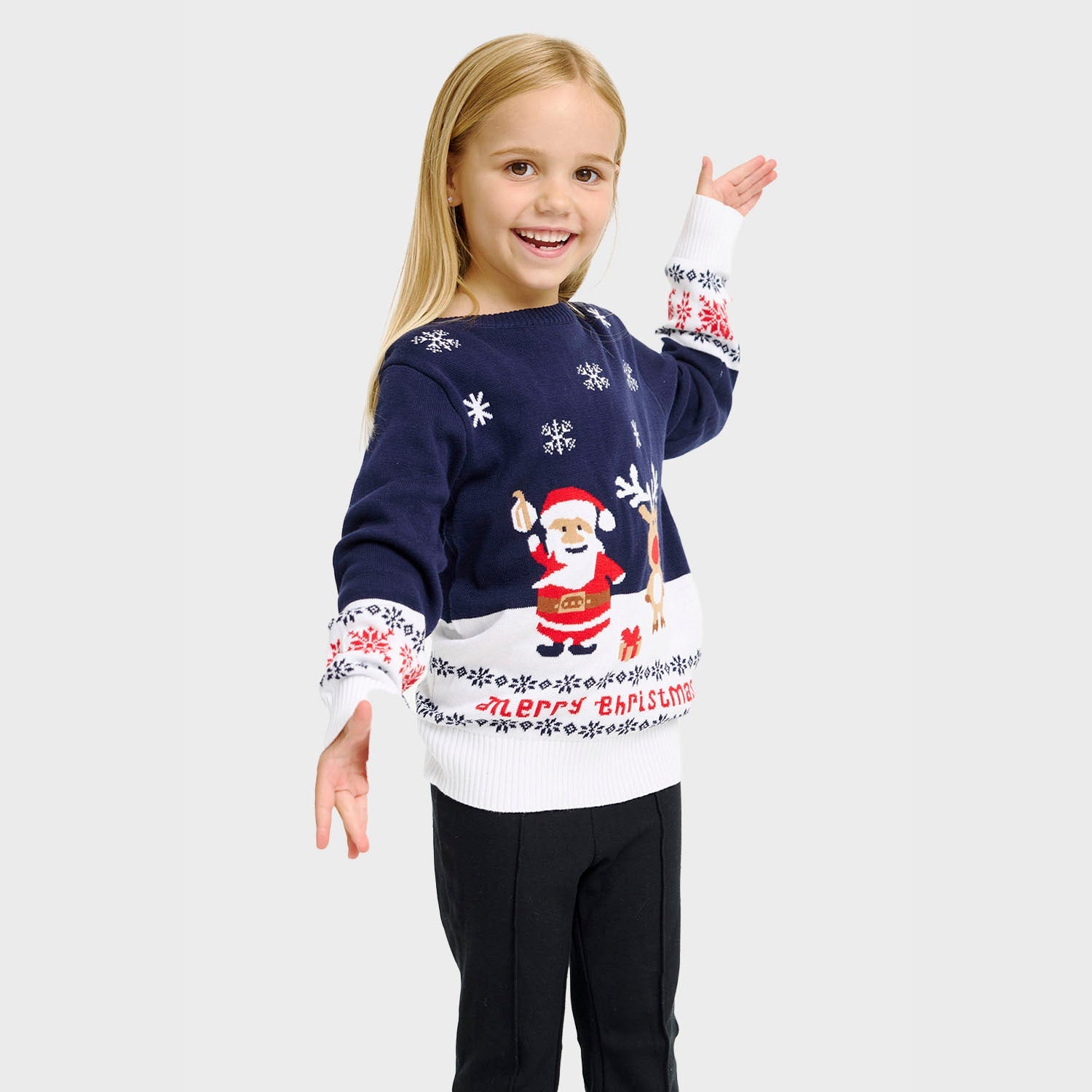 Ett barn som bär en vit och blå jultröja med jultomten och Rudolf på.