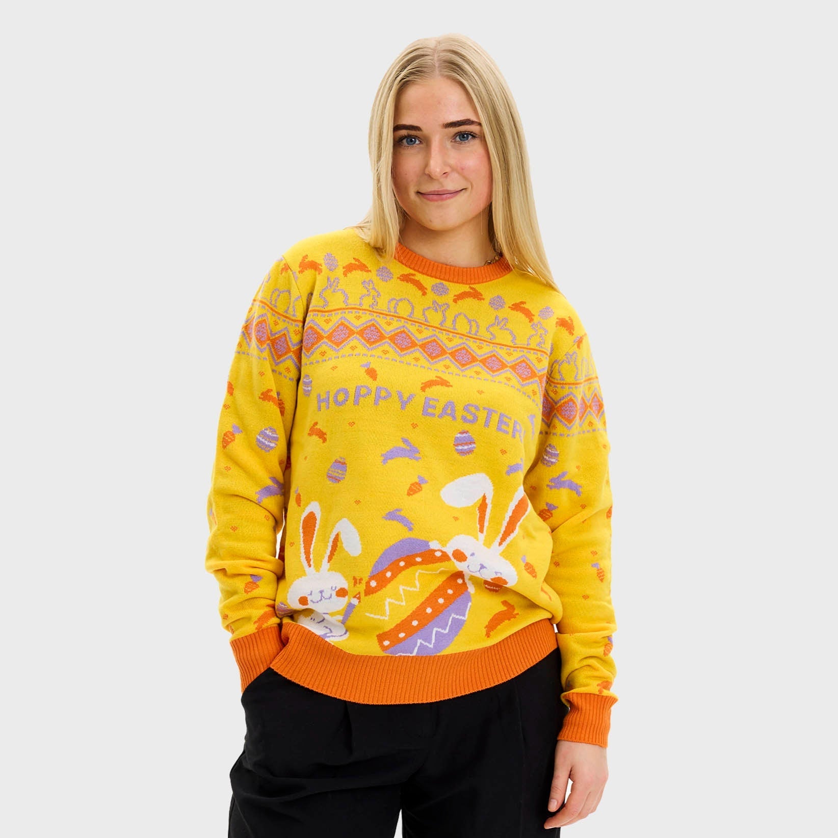 En kvinna i en gul påsktröja med påskägg och kaniner.
