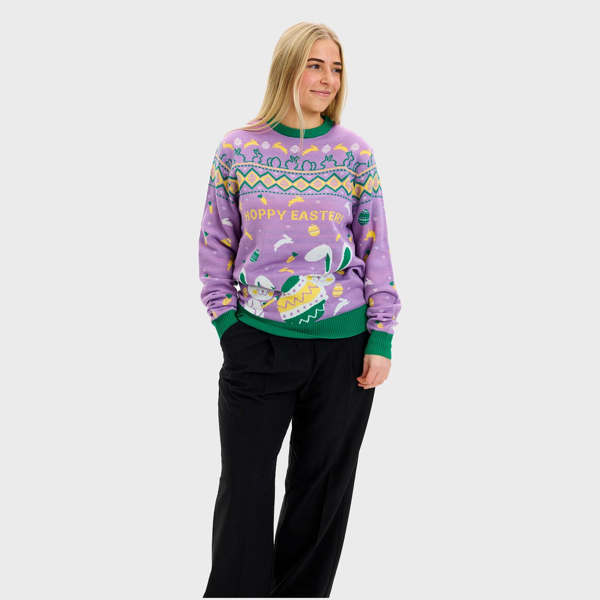 En leende man med ett påskägg klädd i en lila påsktröja med påskägg och kaniner.