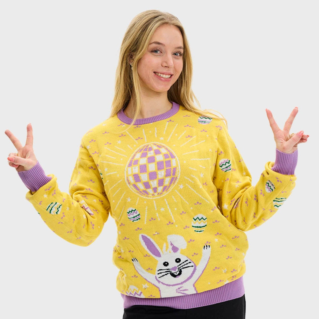 En kvinna klädd i en gul påsktröja med en discokula och en hare.