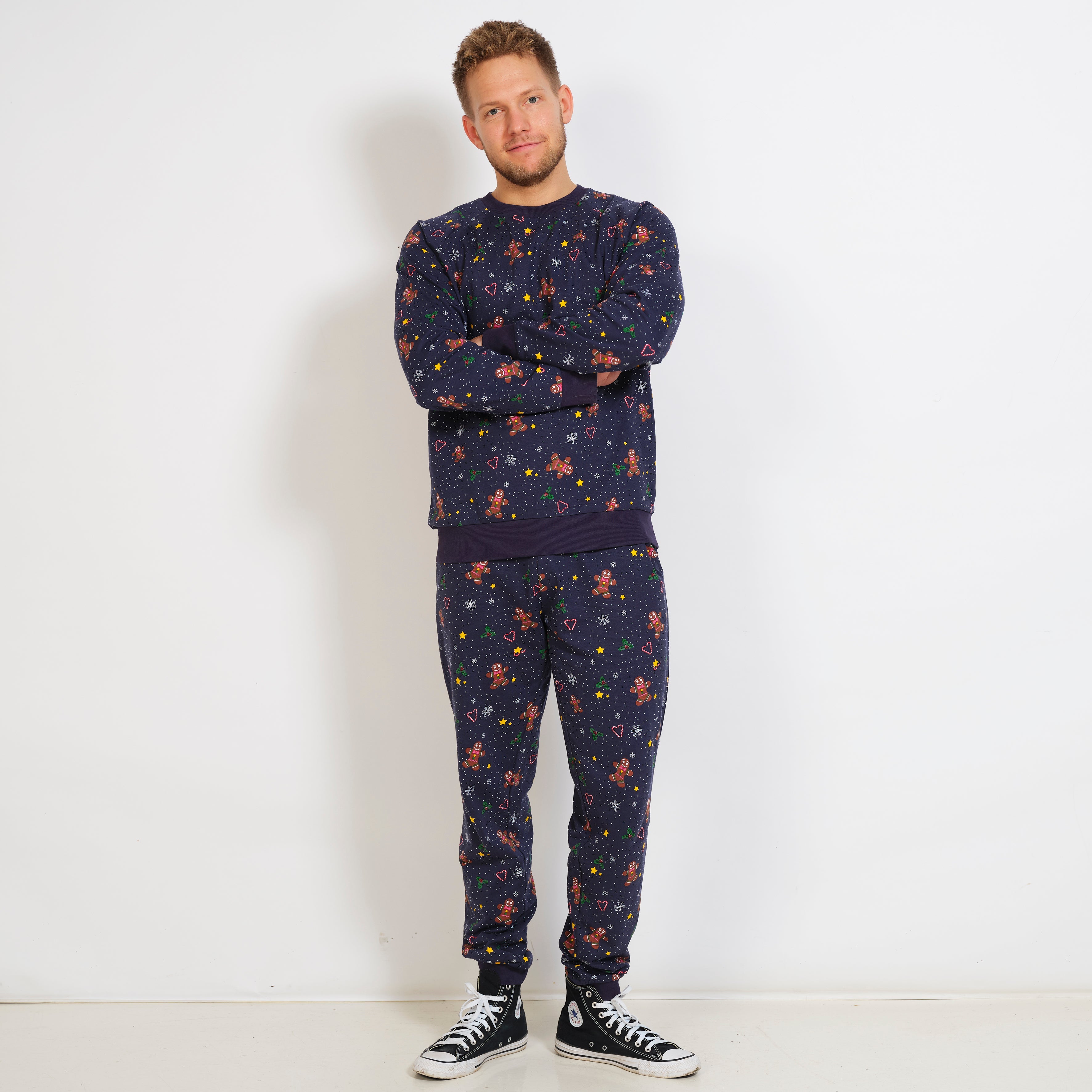 En man med händerna i kors bär en mörkblå jultröja med kakgubbar.
