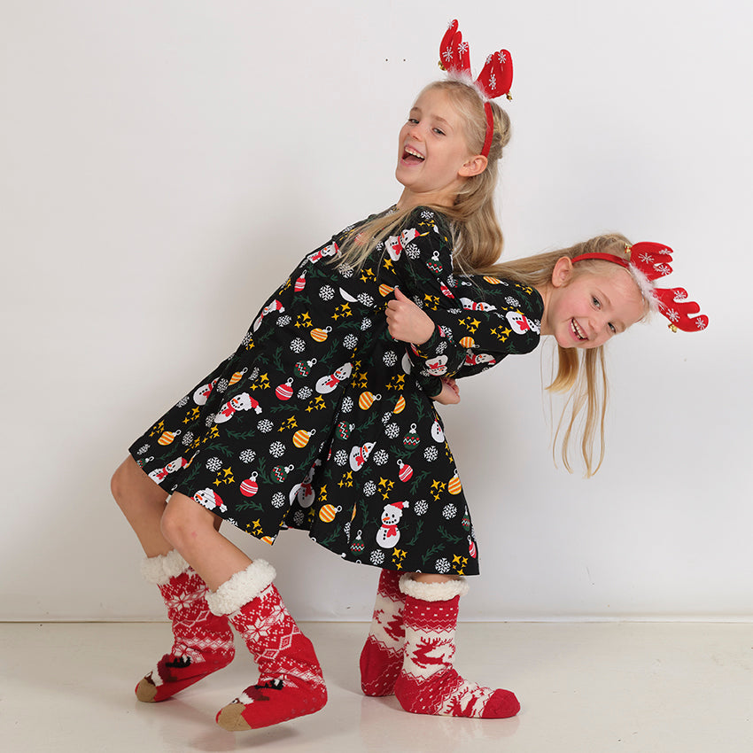 Två lekfulla barn i svarta julklänningar.