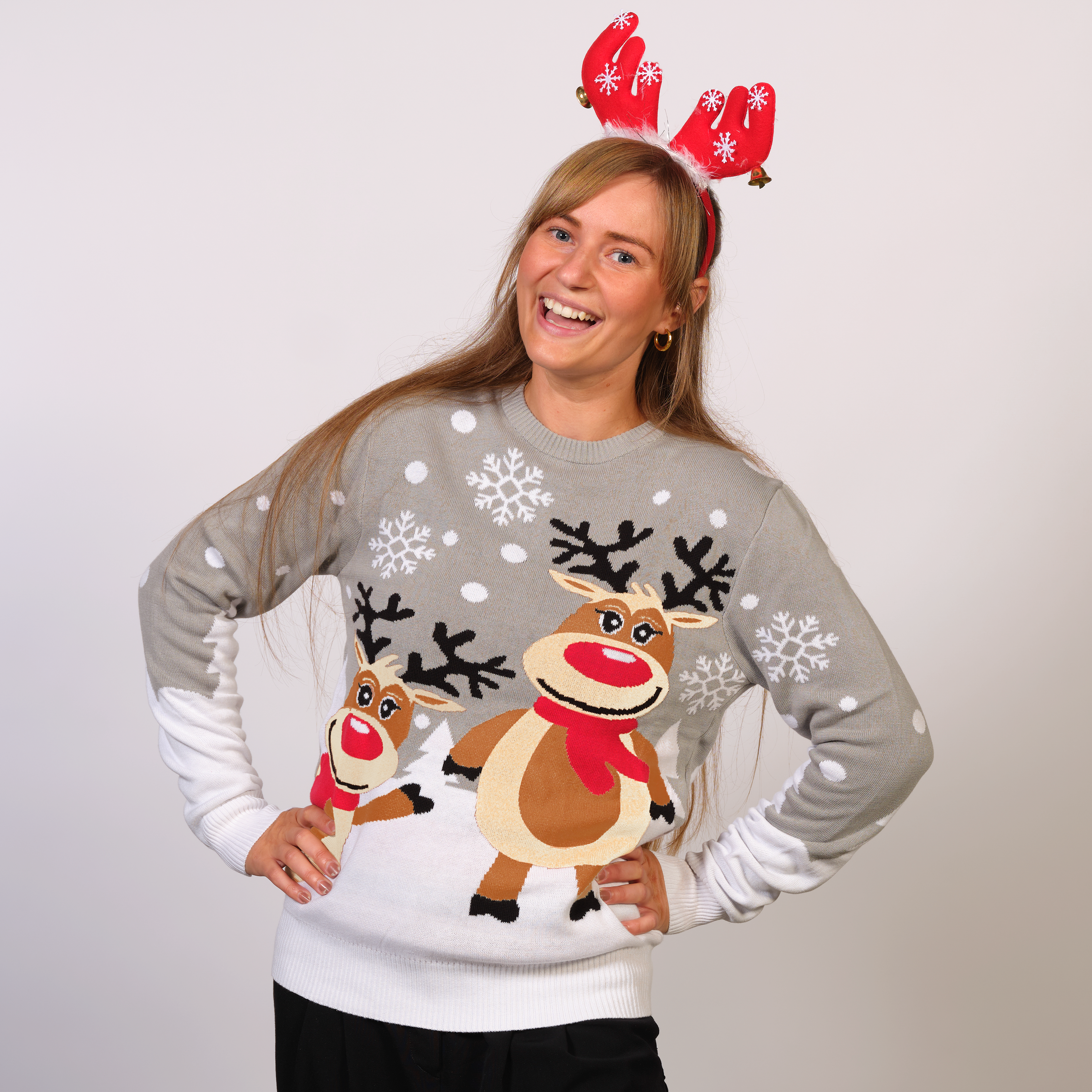 Kvinna i grå jultröja med renar och snöflingor.