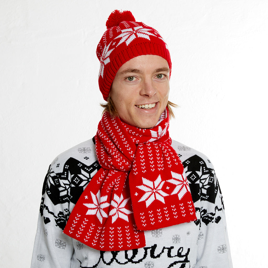 En man med röd mössa och halsduk med snöflingor.