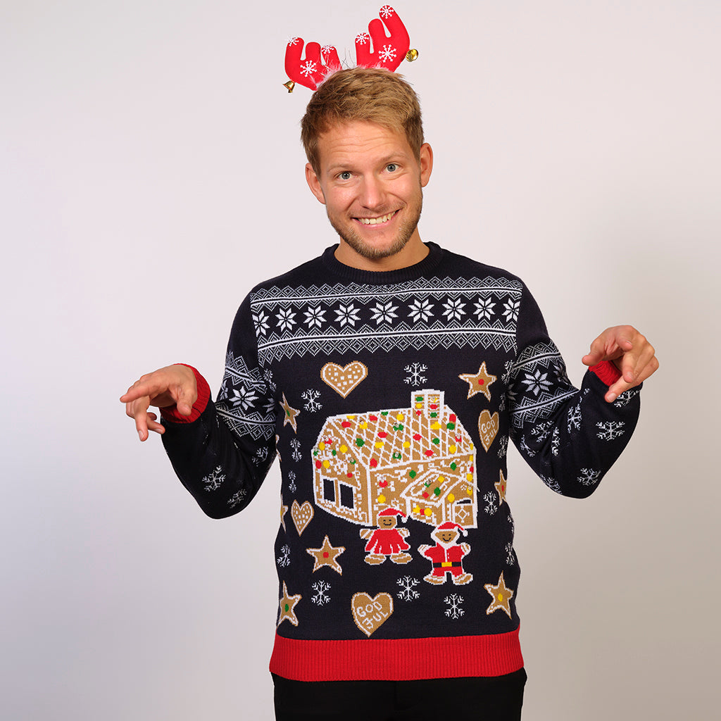 En leende man i jultröja med tårthus och ljus.