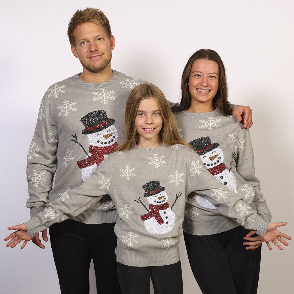 Familj i grå jultröja med snögubbe och snöflingor.