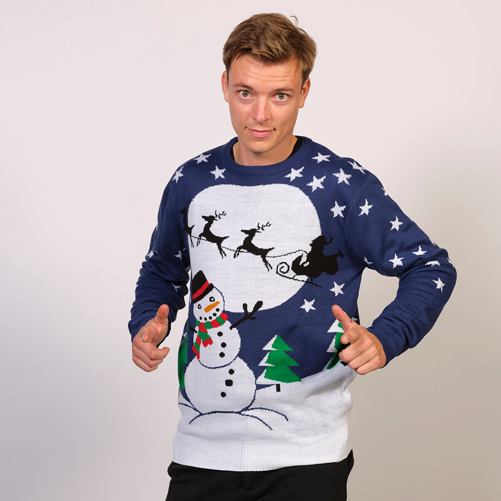 En man i en blå jultröja med en snögubbe och en måne på.