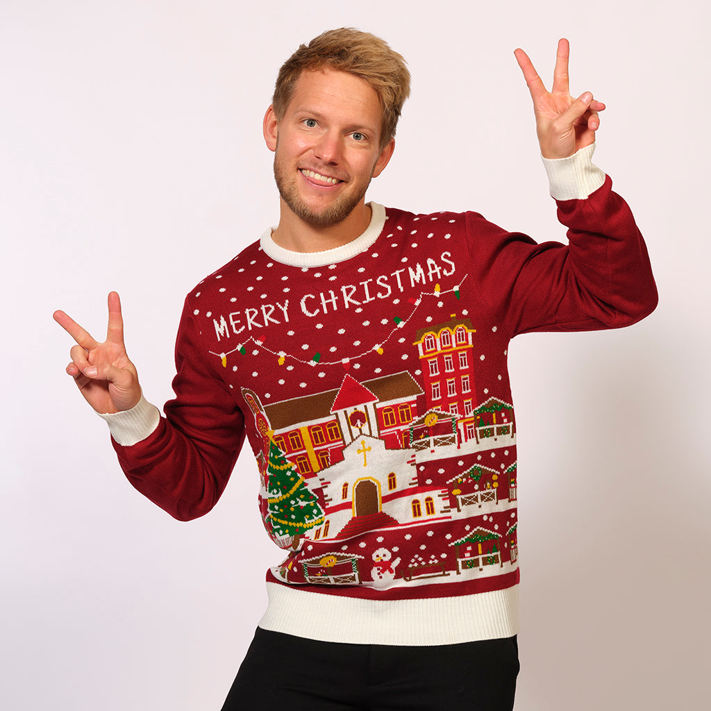 En man i en röd jultröja med en snötäckt stad på.