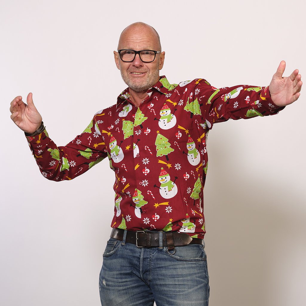 En man poserar iklädd en röd jultröja med tomtar och julgranar på.