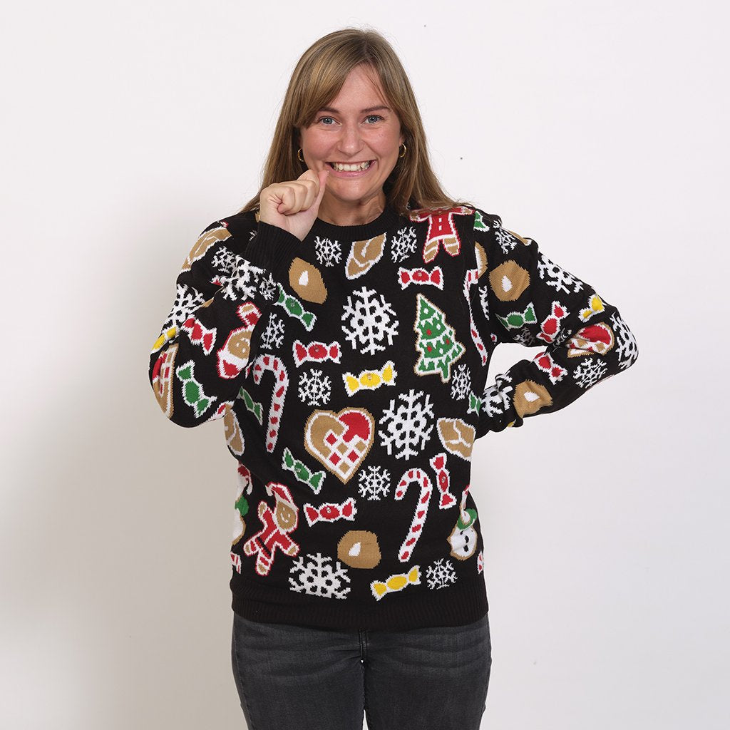 En kvinna i svart jultröja med tårtmän och godis.