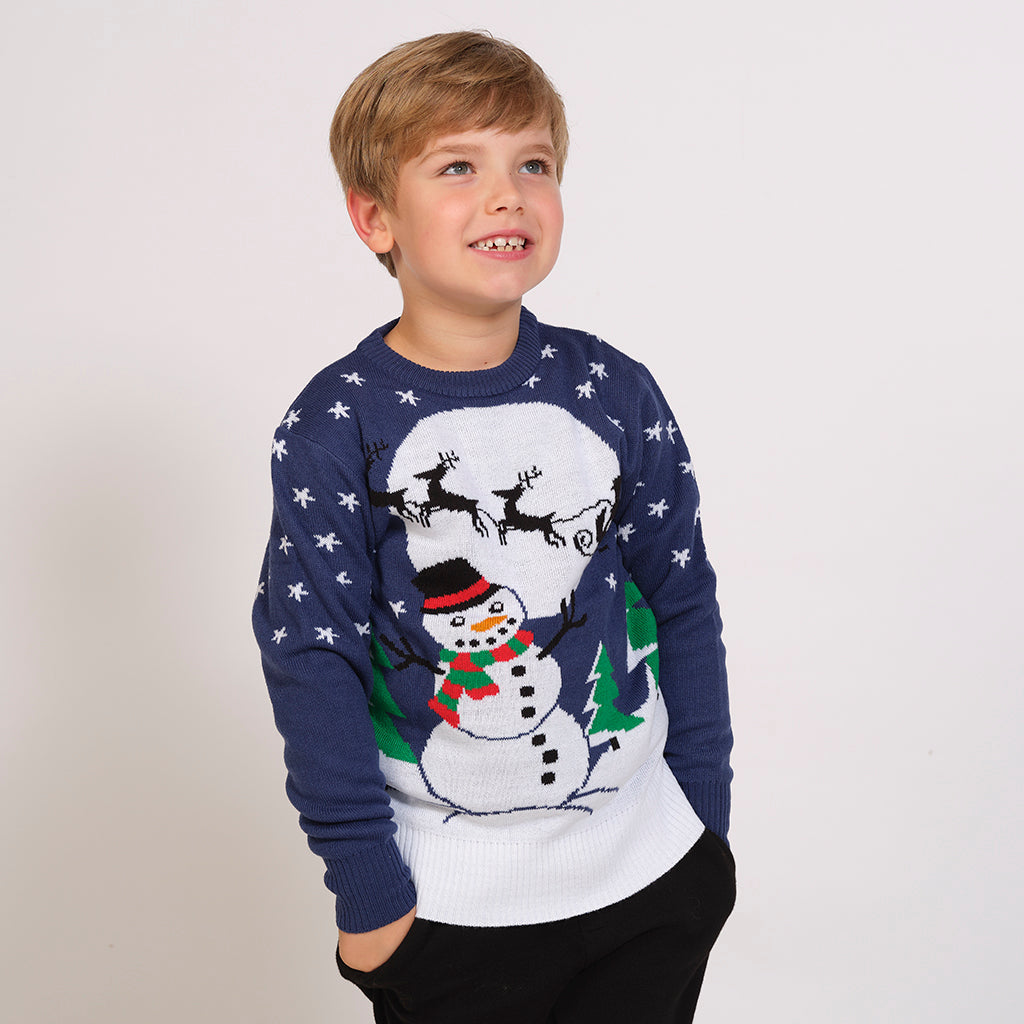 Ett barn i en blå jultröja med en snögubbe och en måne.