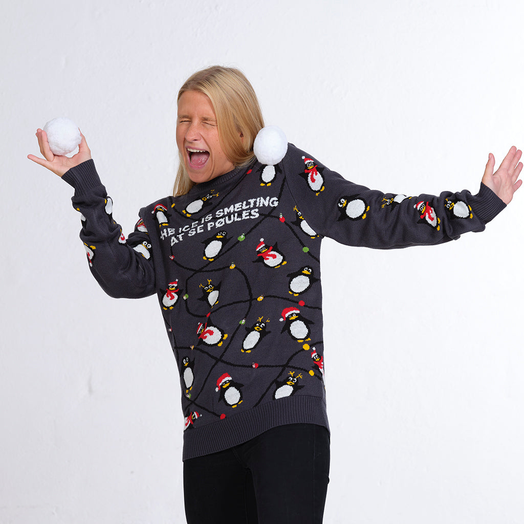 En kvinna i en grå jultröja med pingviner och ljus.