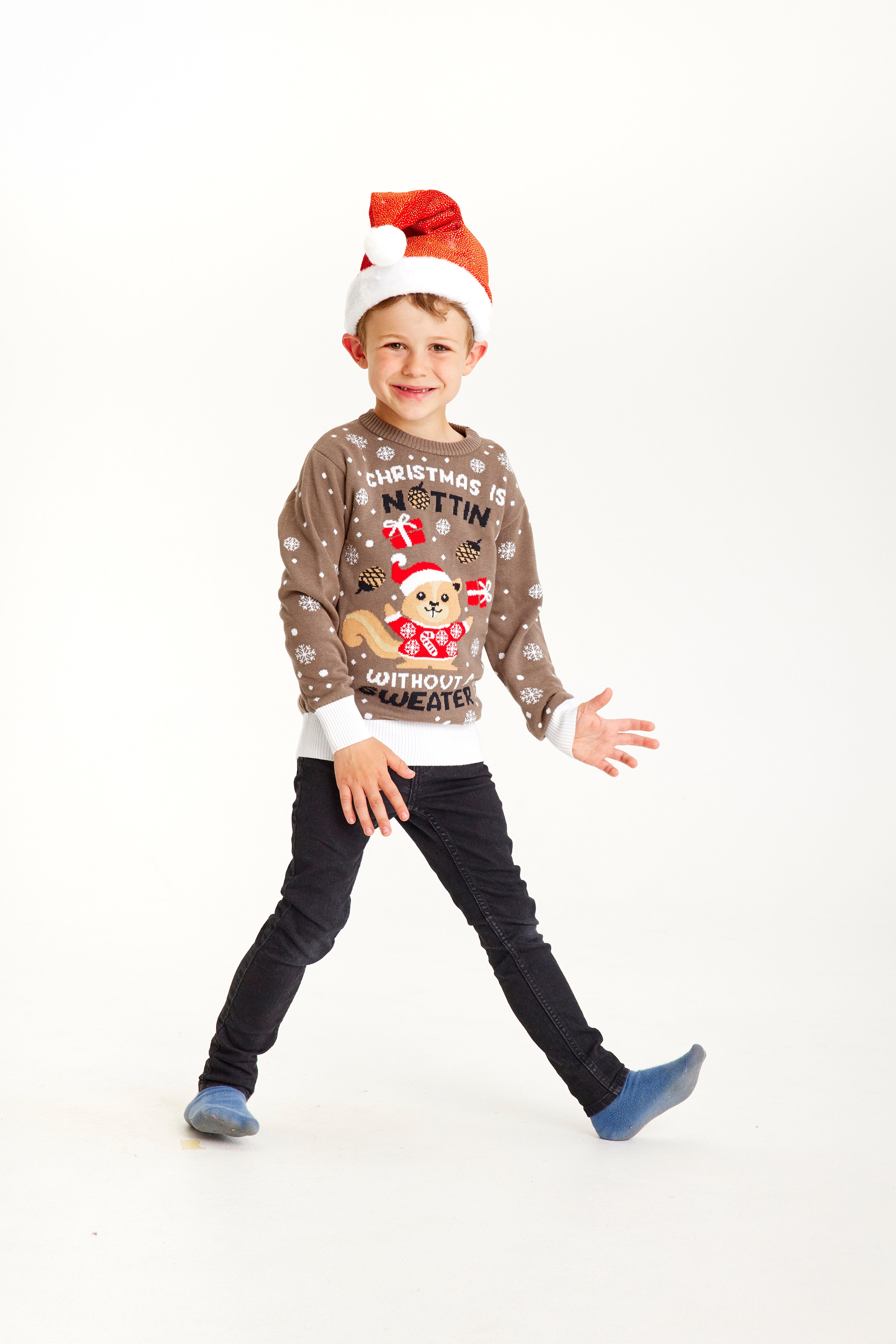 Ett leende barn i brun jultröja med snöflingor.