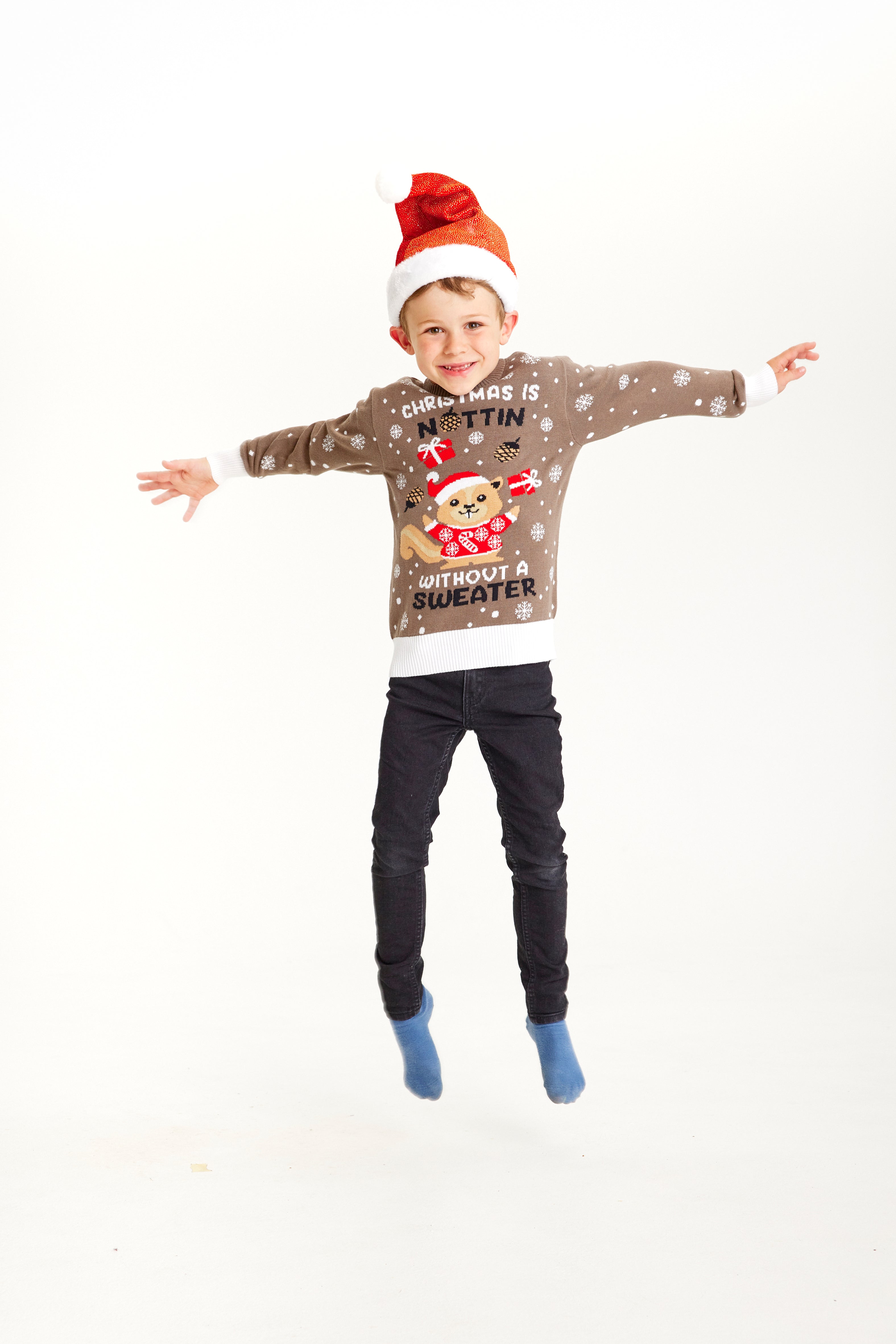 Ett studsande barn i brun jultröja med snöflingor.