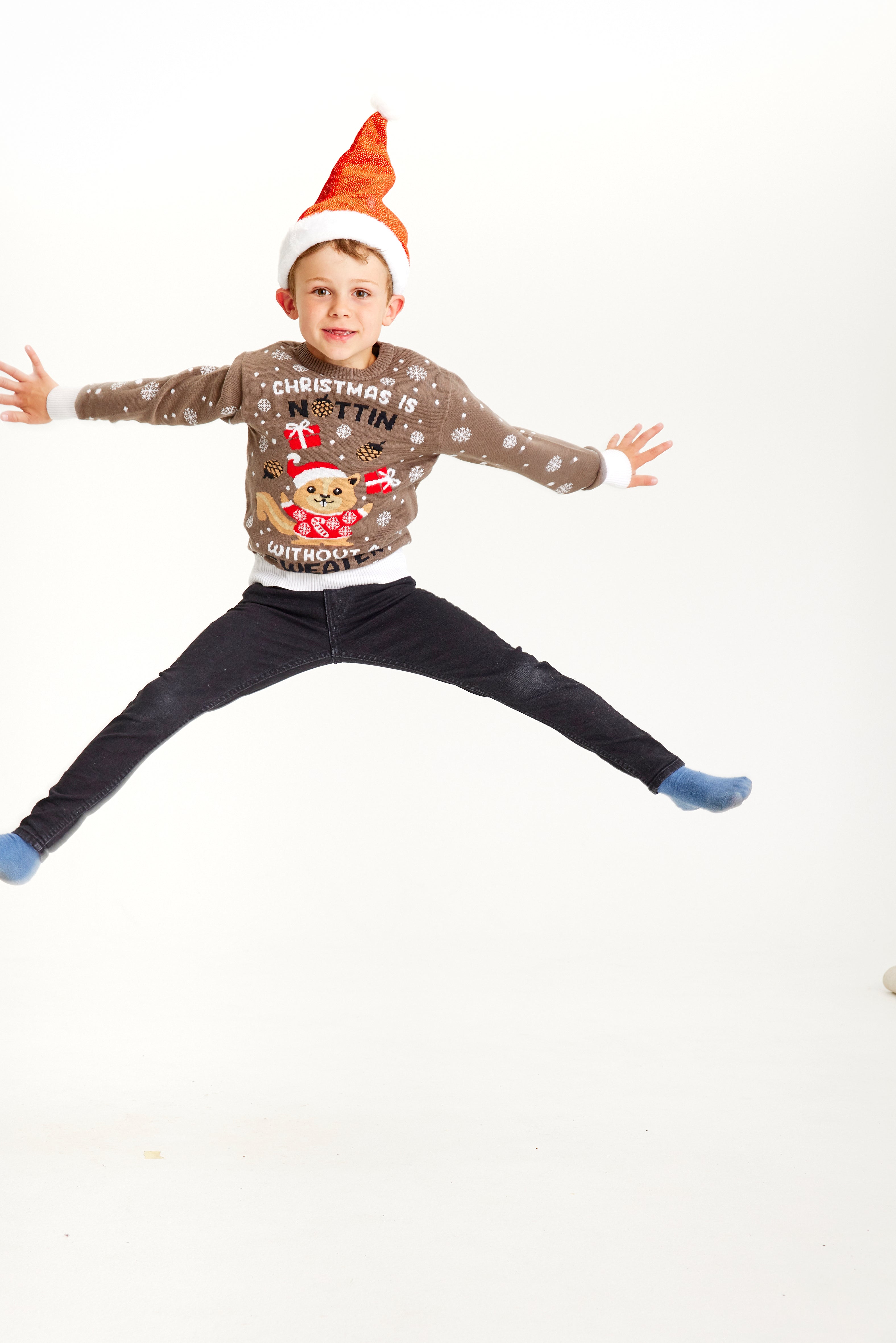 Ett hoppande barn klädd i en brun jultröja med snöflingor.