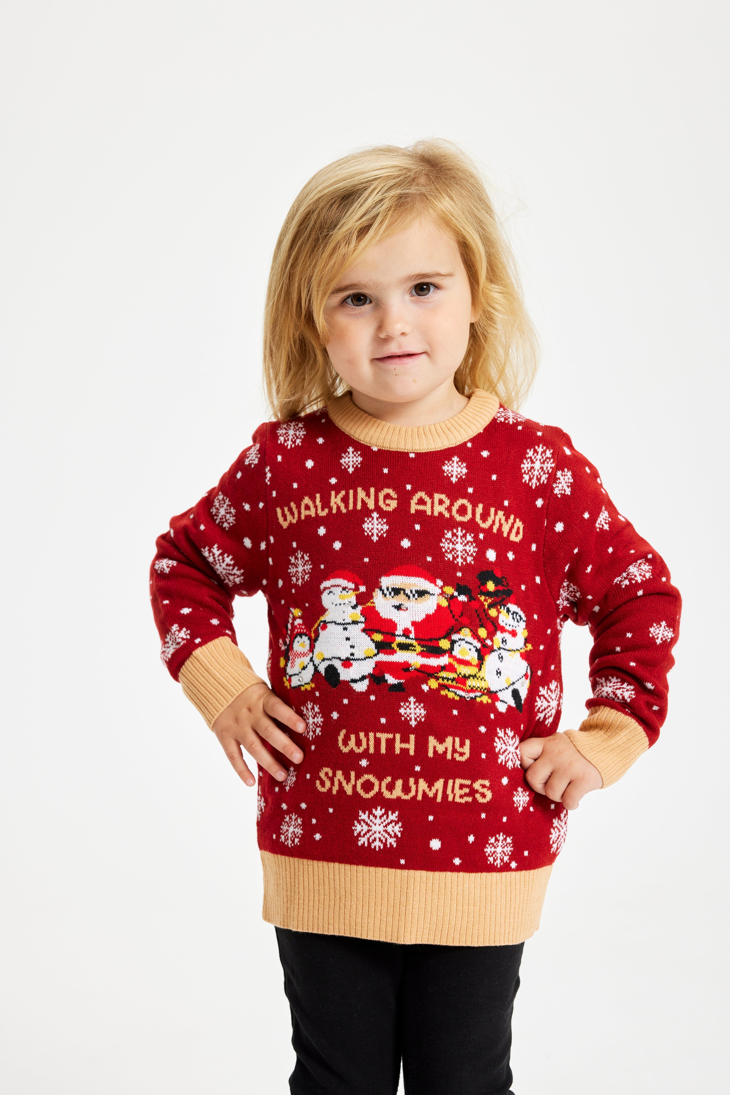 Ett sött barn som bär en röd jultröja med ljus och texten 