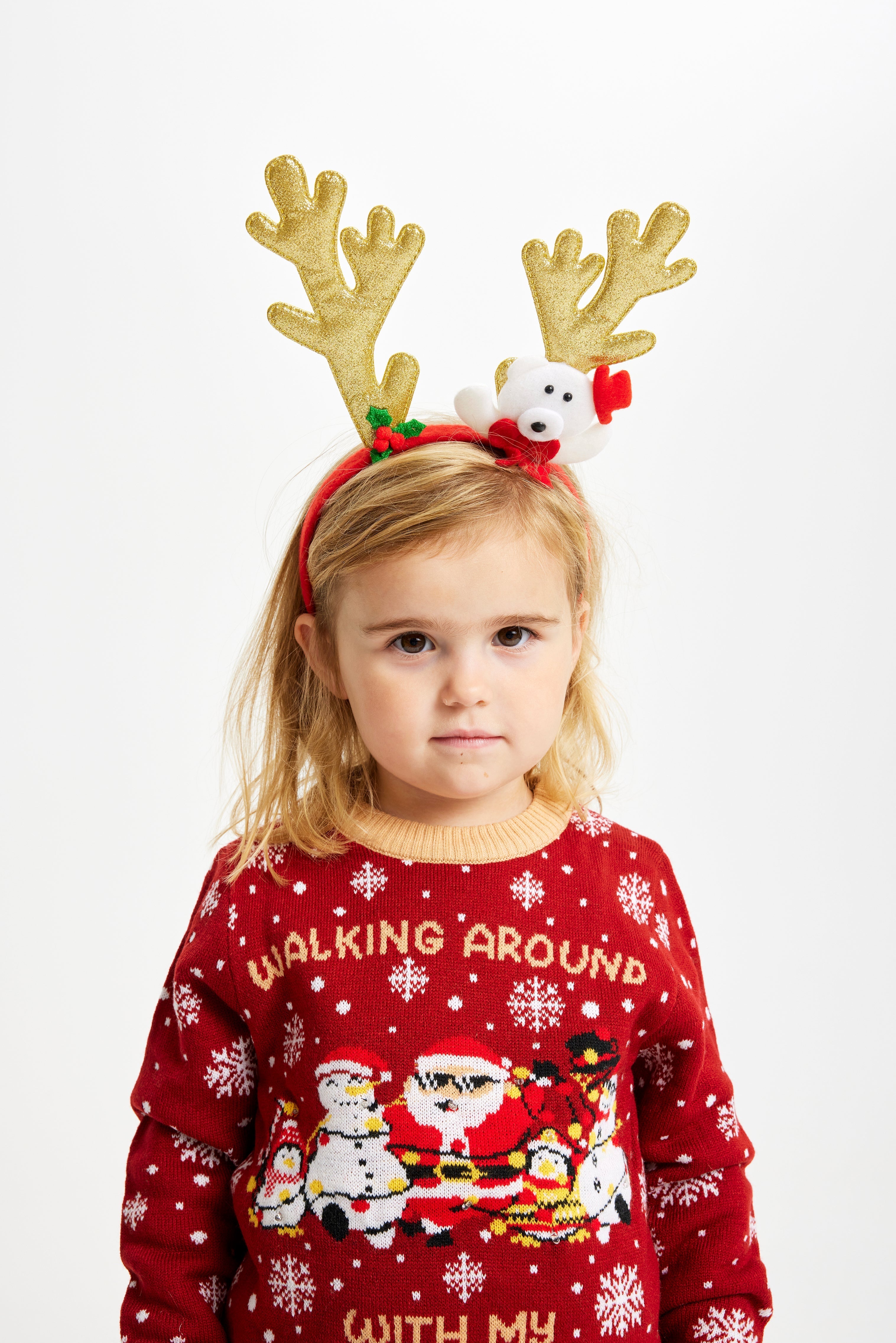 Ett litet barn med renhorn och en röd jultröja med lampor och texten 