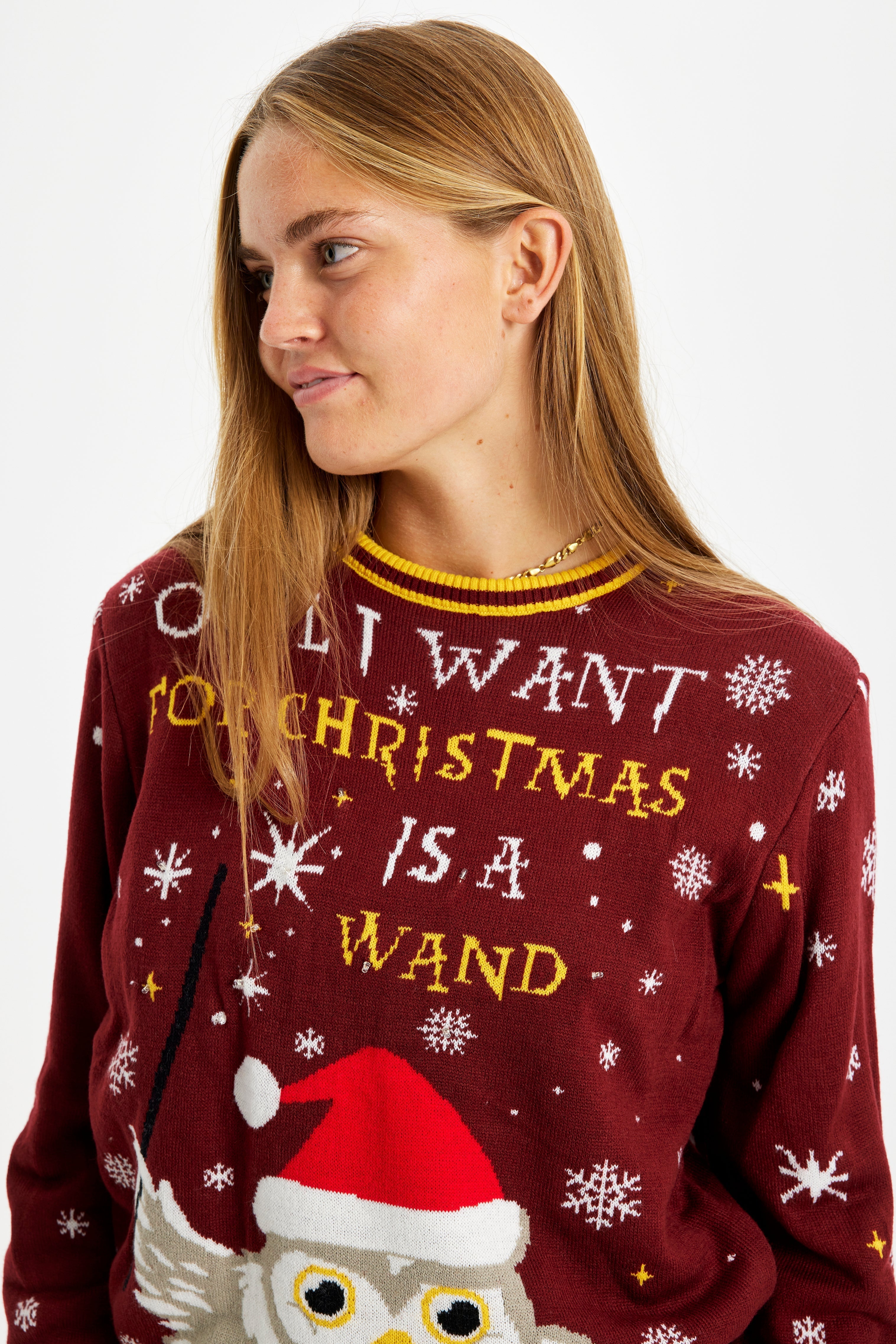 En kvinna som tittar åt sidan iklädd en röd jultröja med texten 