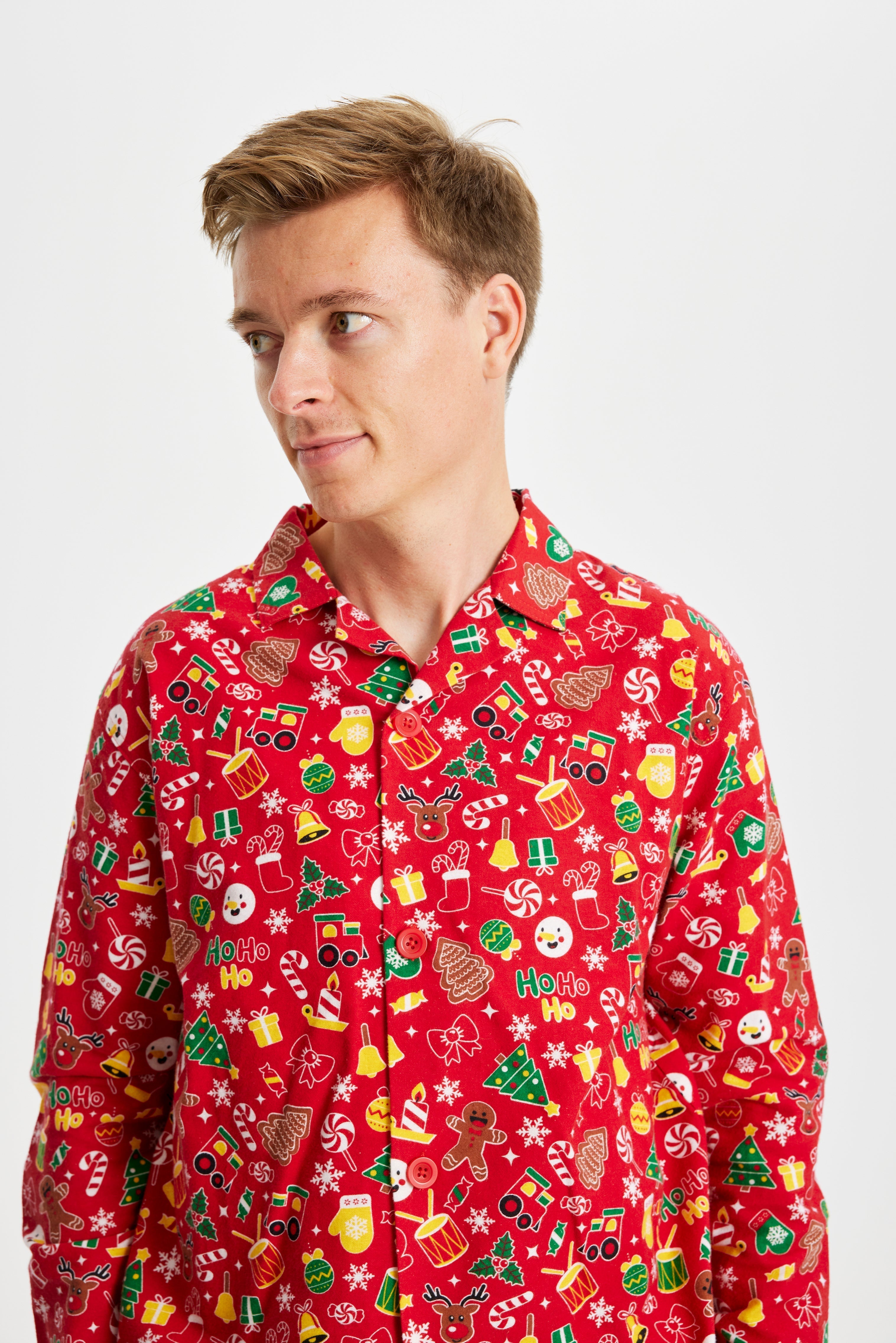 En man poserar i sin vackra röda julpyjamas med julsaker.