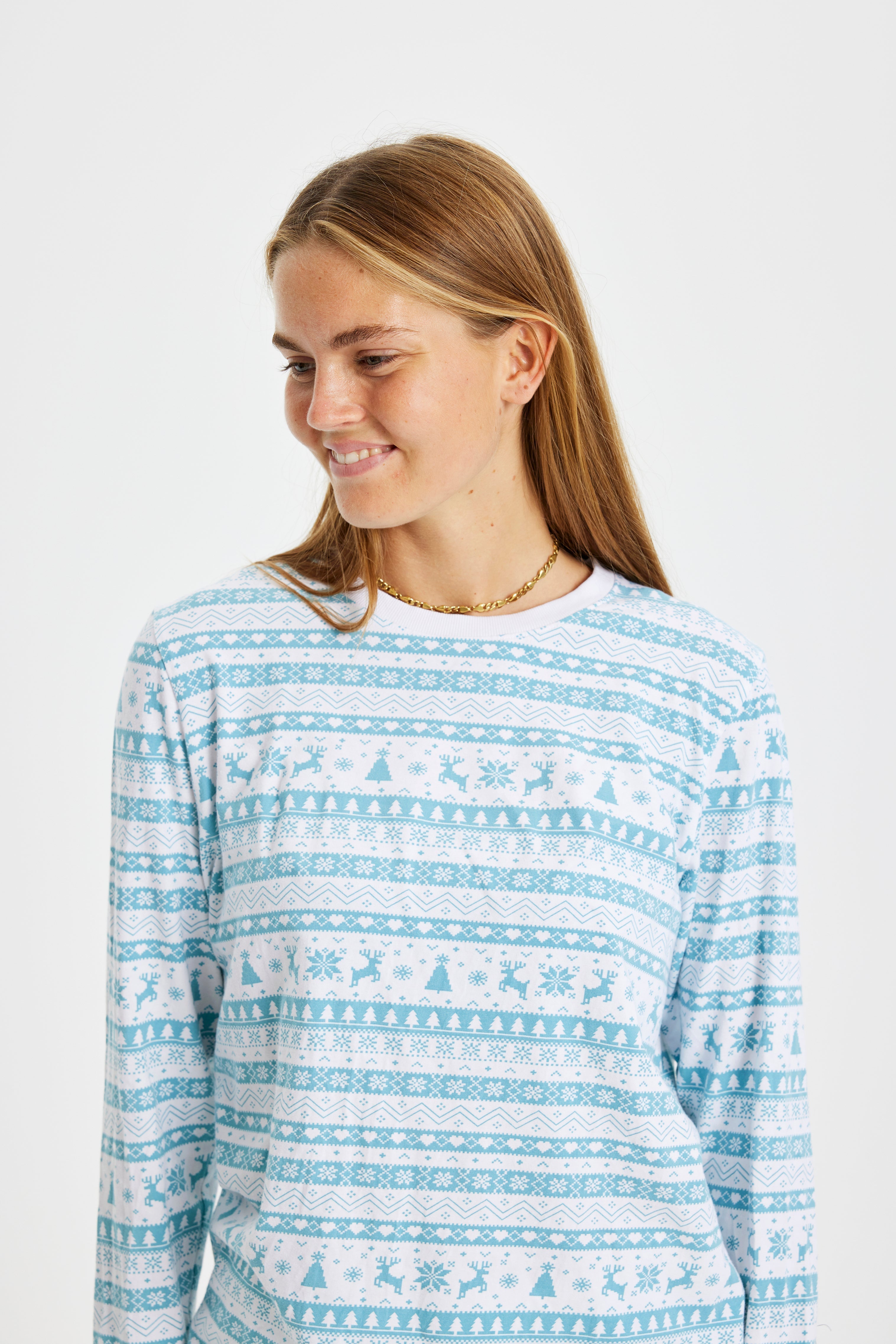 En leende kvinna klädd i ljusblå julpyjamas.