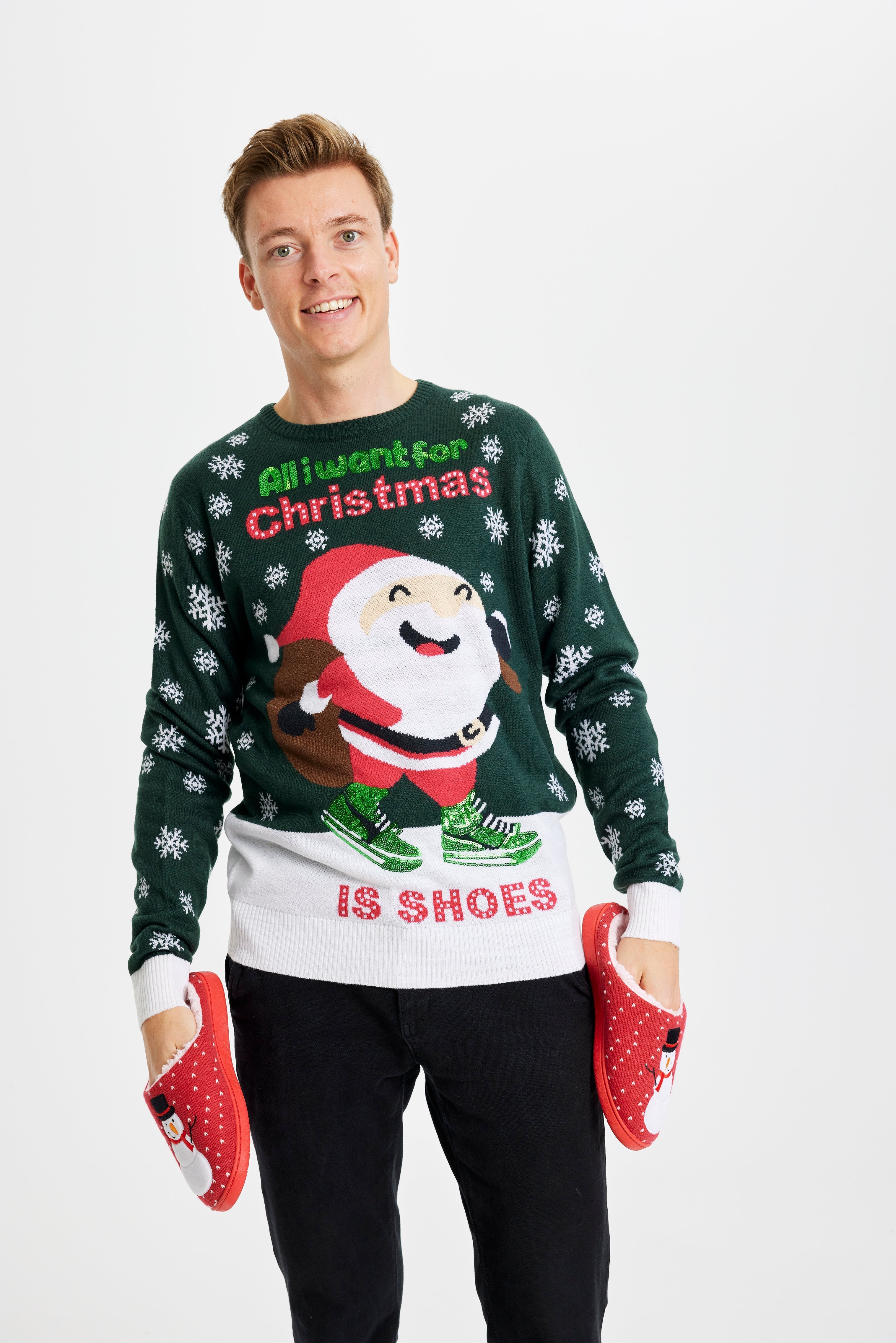 En leende man klädd i en grön jultröja med texten 