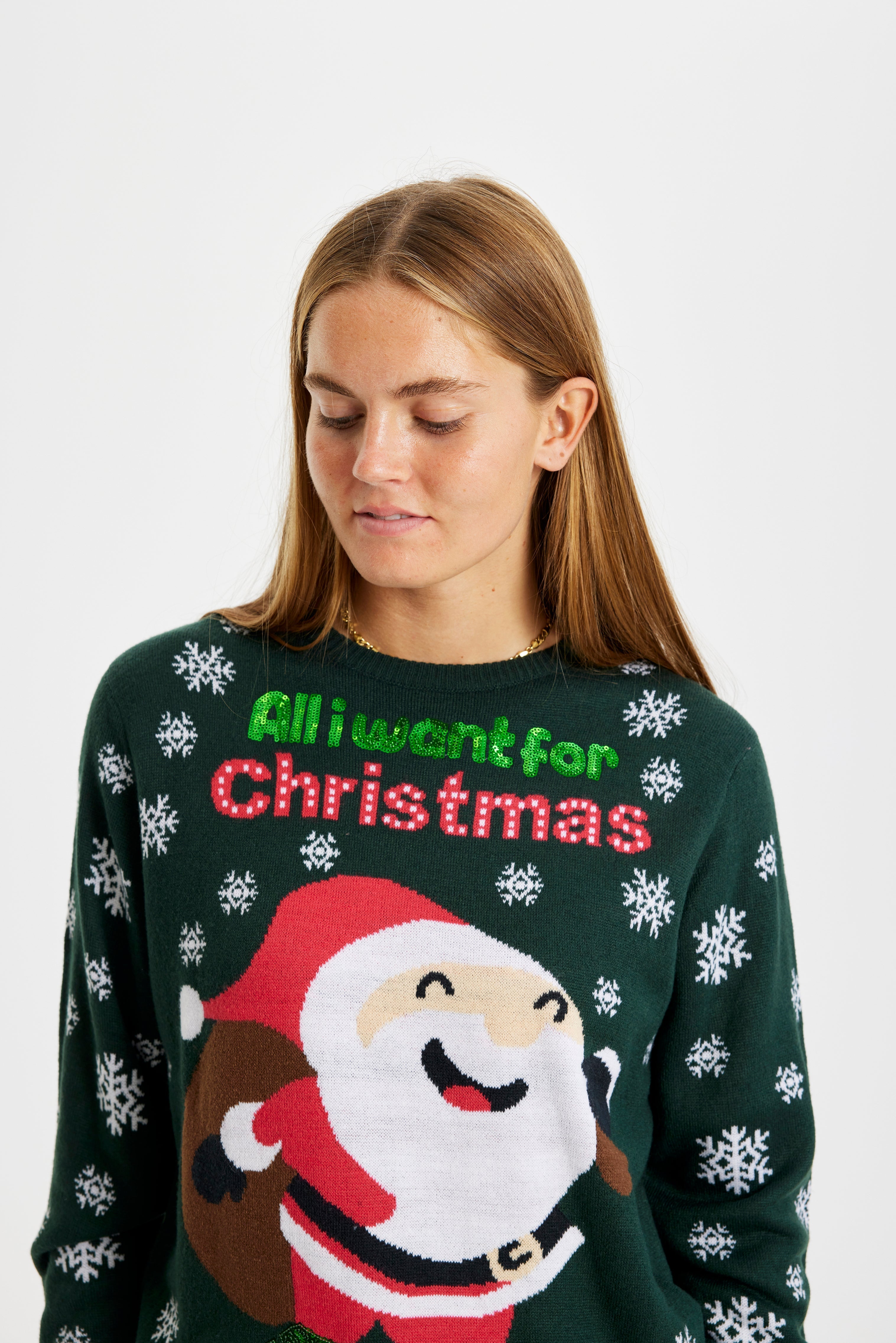 En kvinna som tittar ner i en grön jultröja med texten 