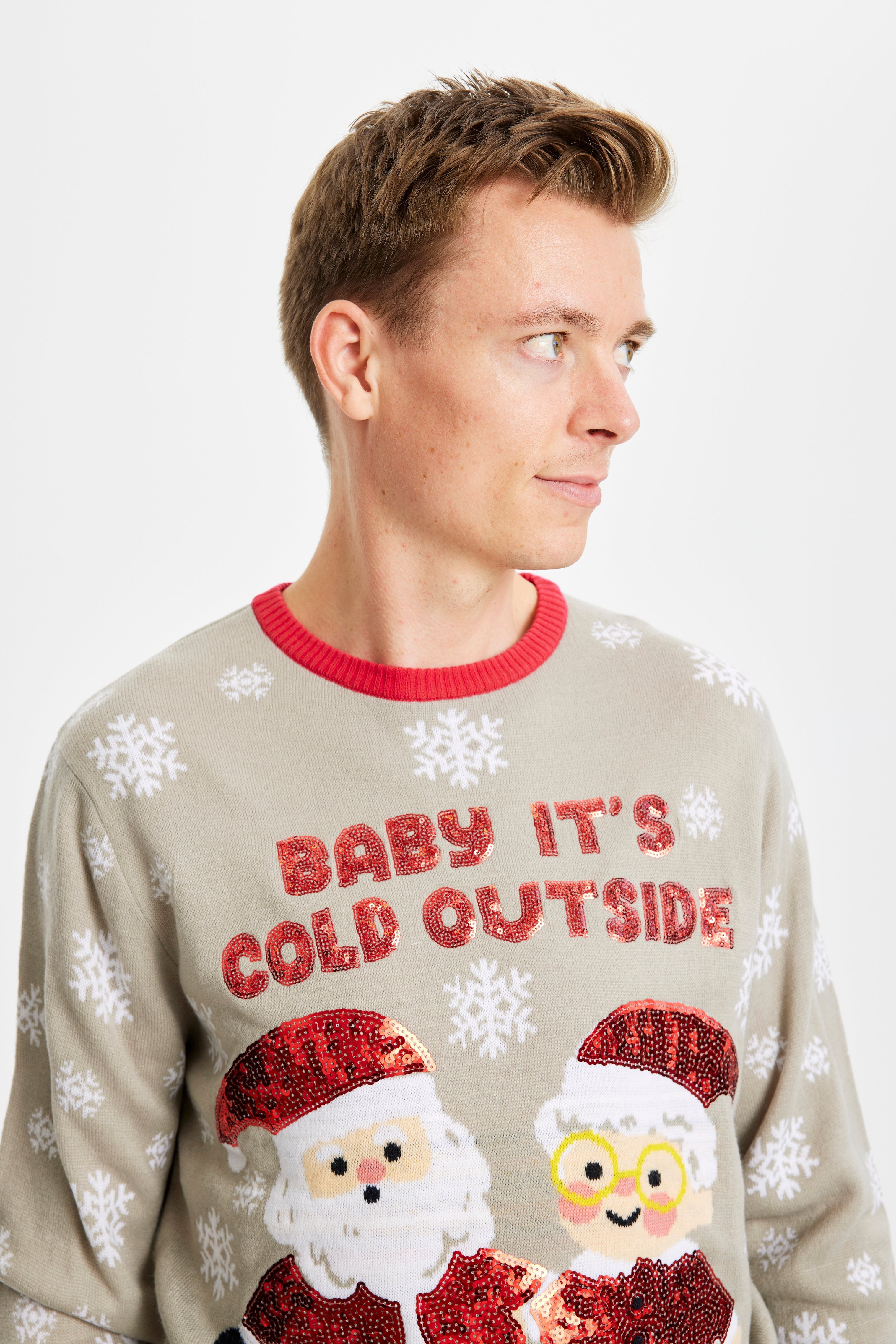 En man som tittar åt sidan i en grå jultröja med citatet 