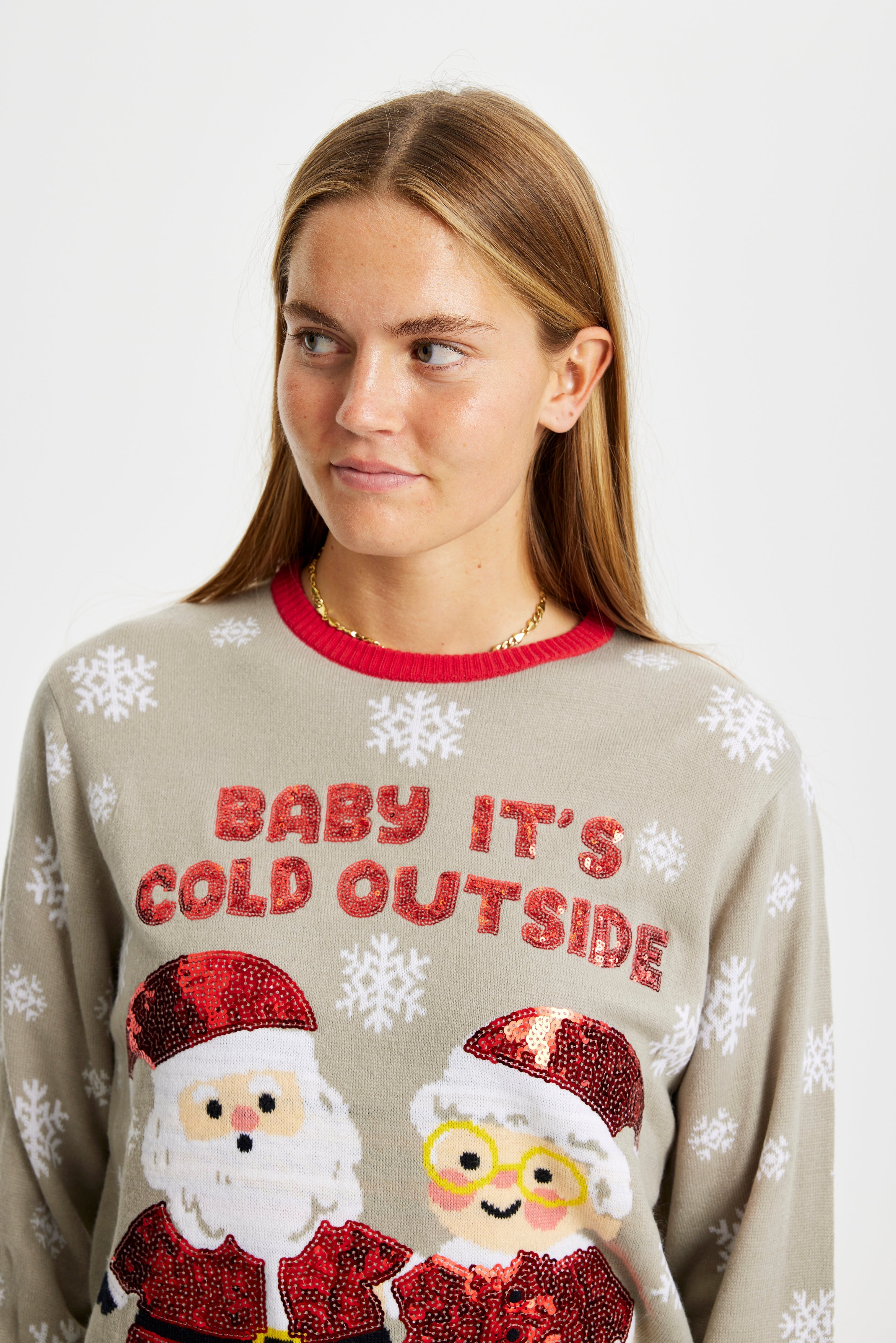 En kvinna tittar åt sidan i en grå jultröja med texten 