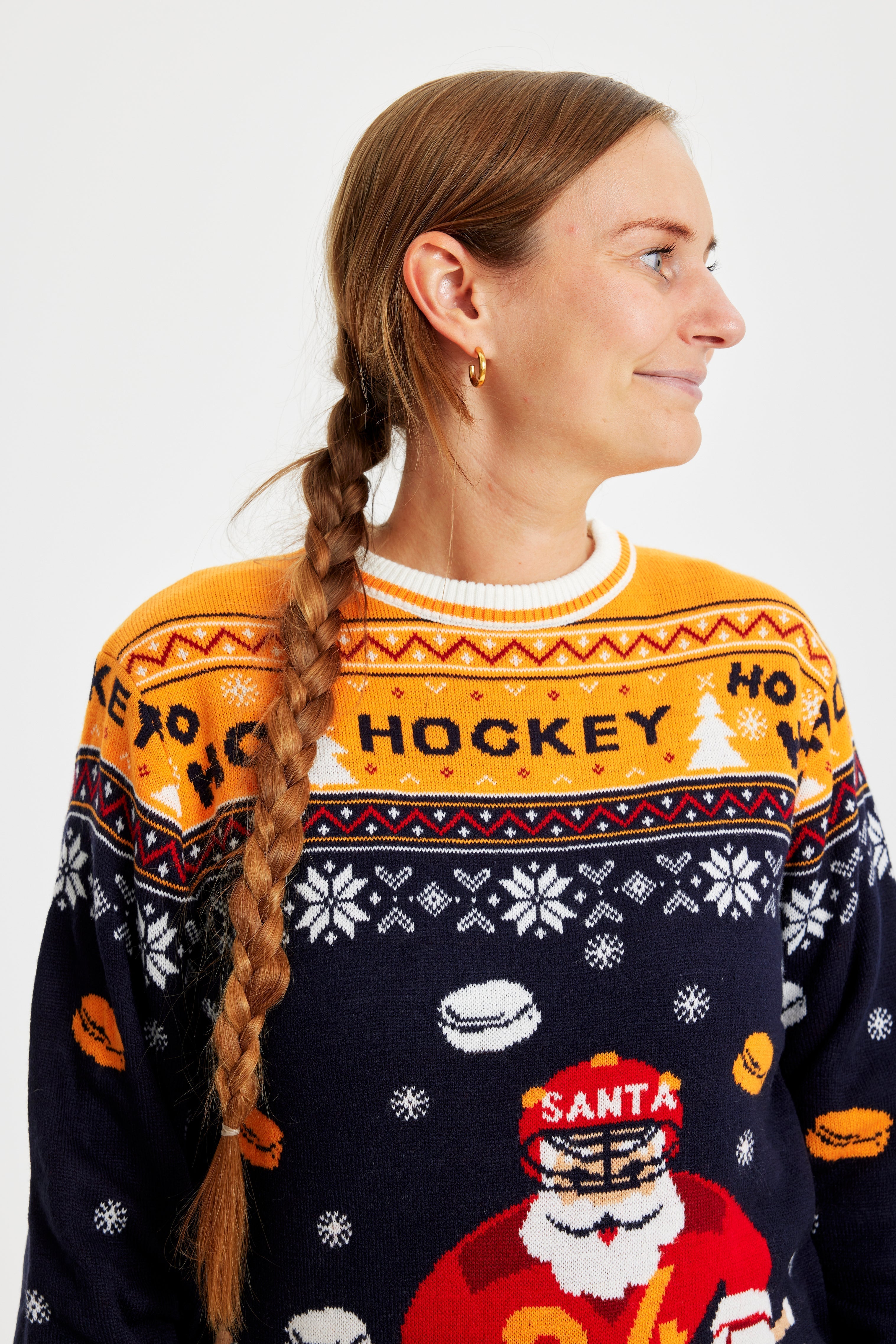 En kvinna som är vänd åt sidan och bär en jultröja med en jultomte som spelar hockey.