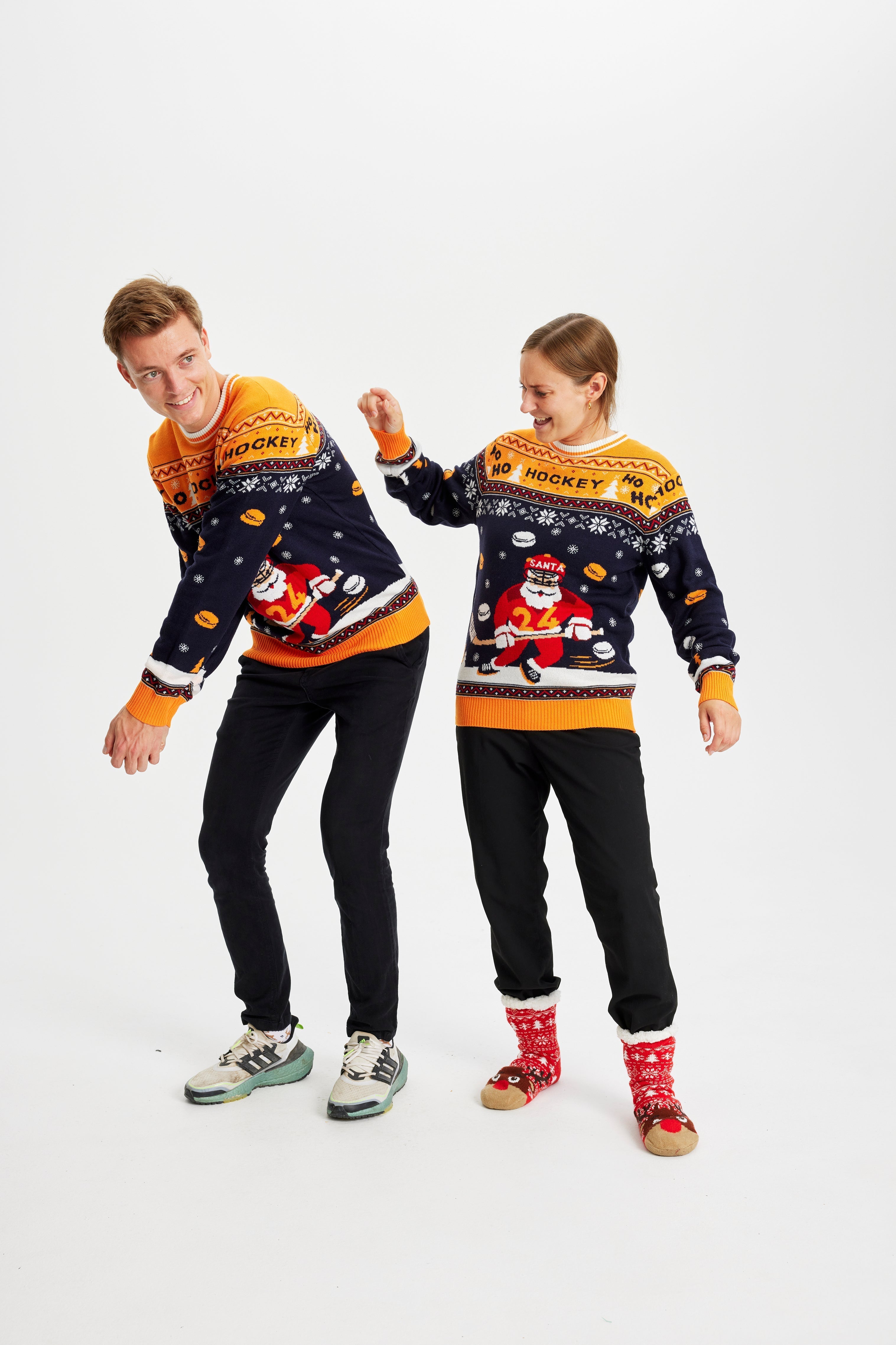 Ett par poserar iförda en jultröja med en tomte som spelar hockey.