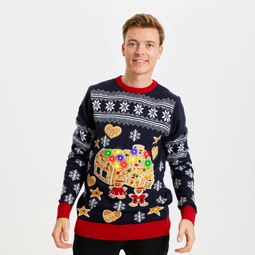 En man i jultröja med tårthus och ljus.