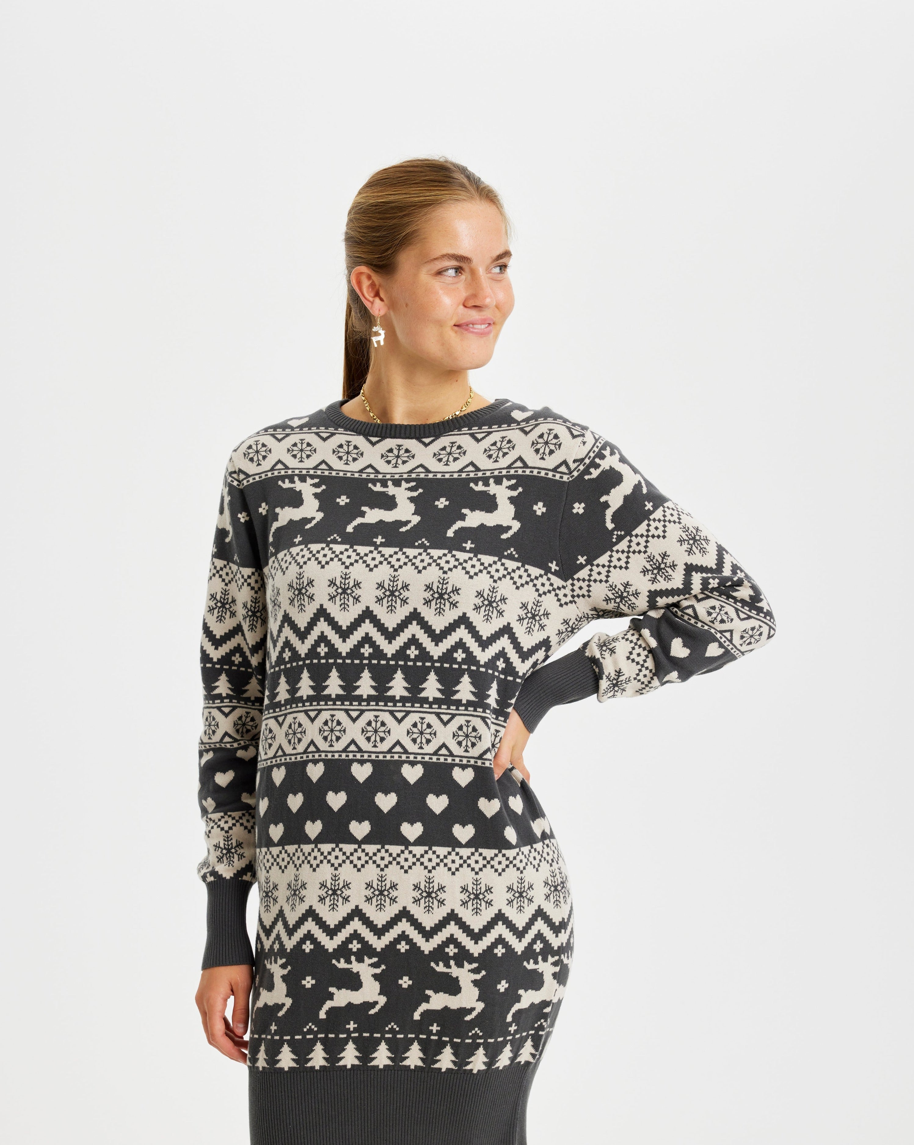 En kvinna tittar åt sidan och är klädd i en gråmönstrad julklänning.