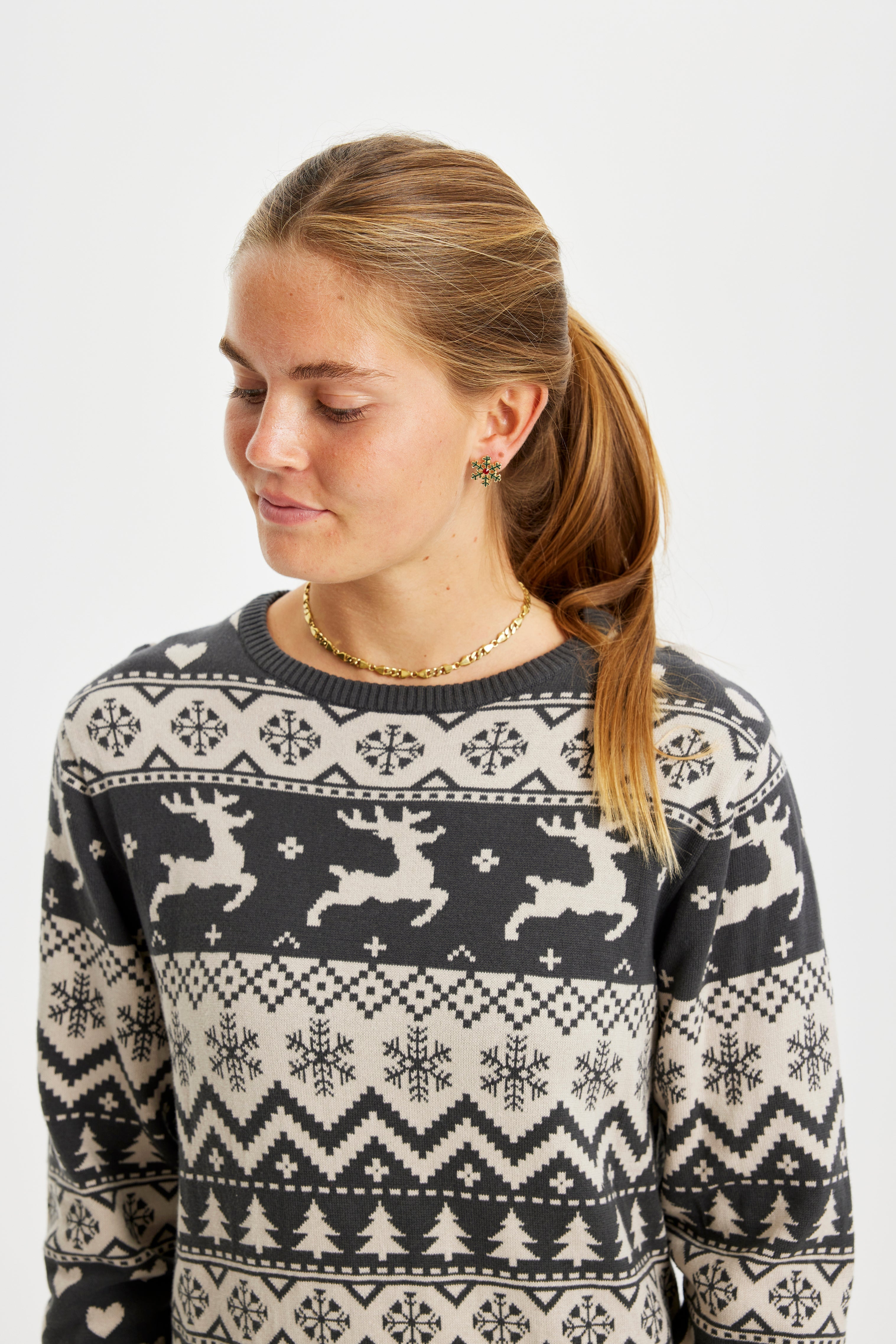 En kvinna som tittar ner har på sig en gråmönstrad julklänning.