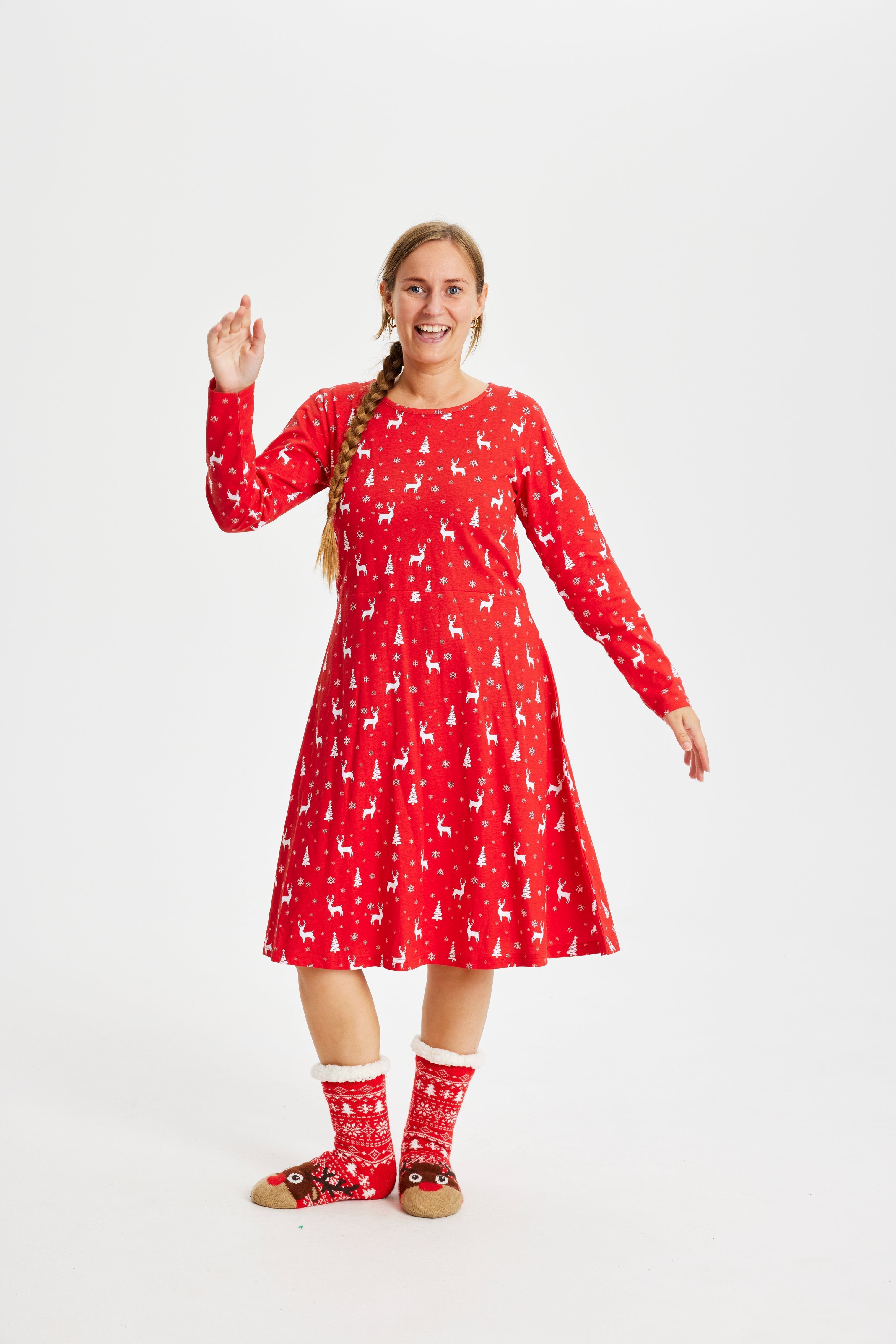 En kvinna med händerna i luften klädd i en röd julklänning med tryck.