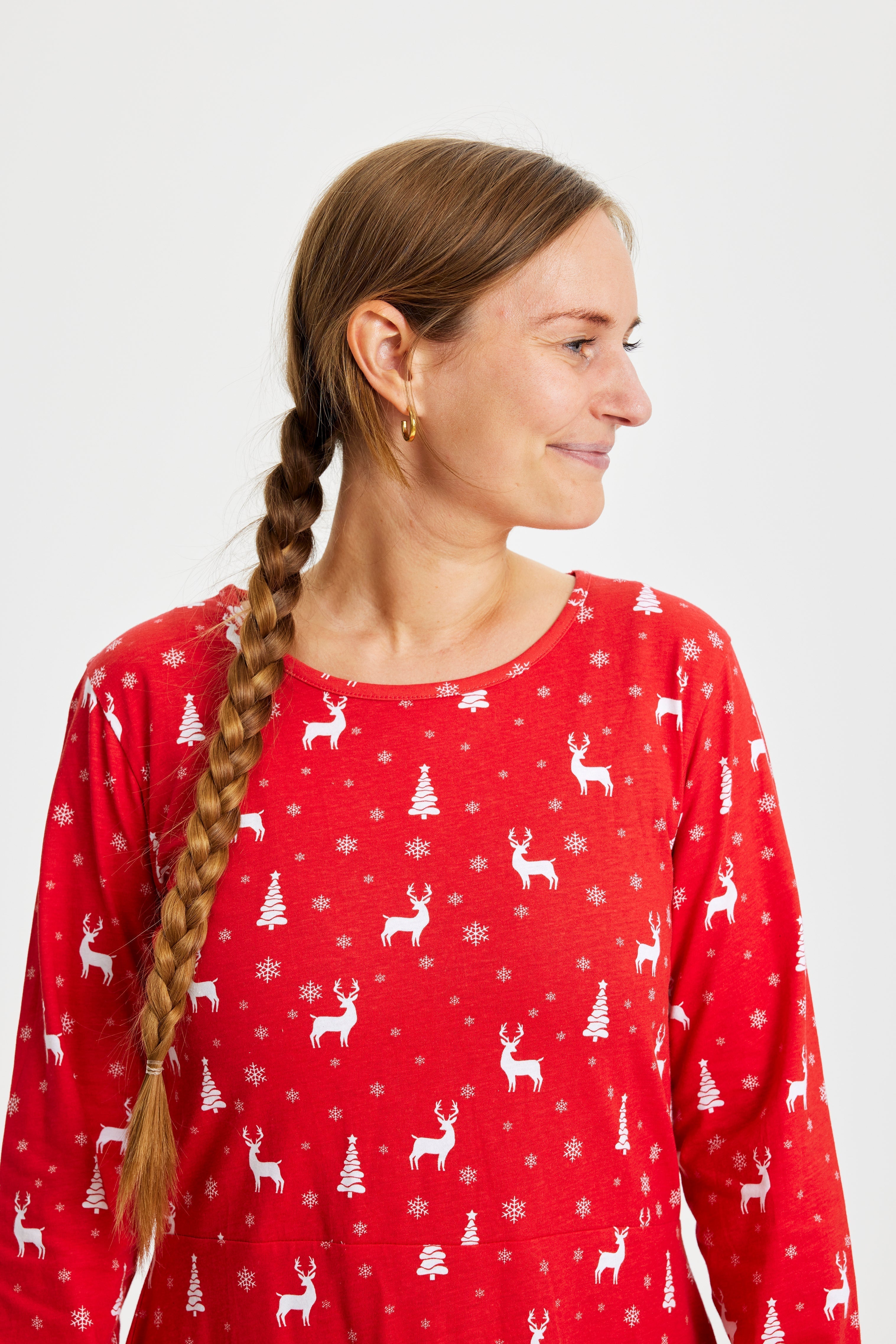 En kvinna tittar åt sidan och är klädd i en röd julklänning med tryck.