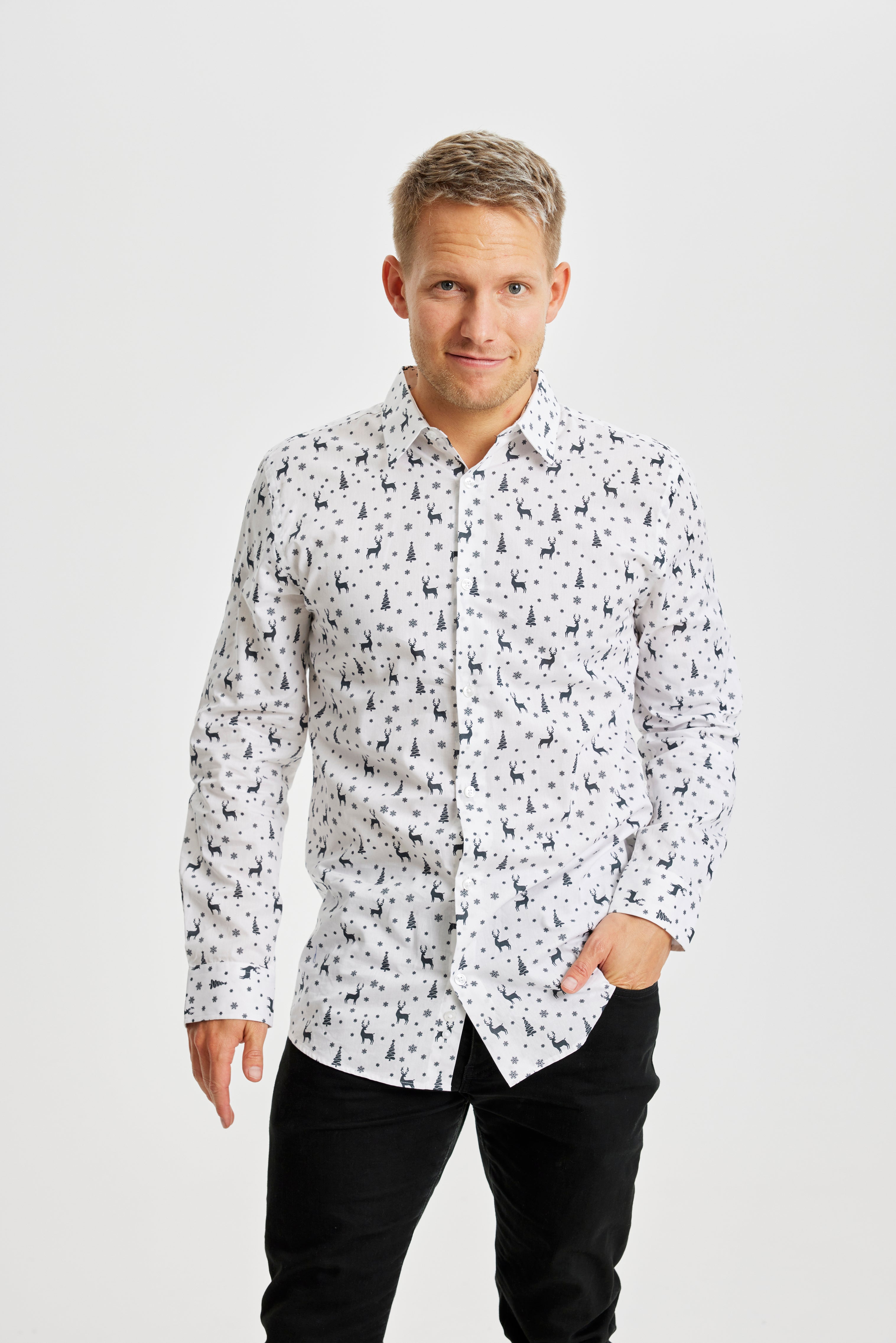 En leende man i vit julskjorta med julgranar och renar på.