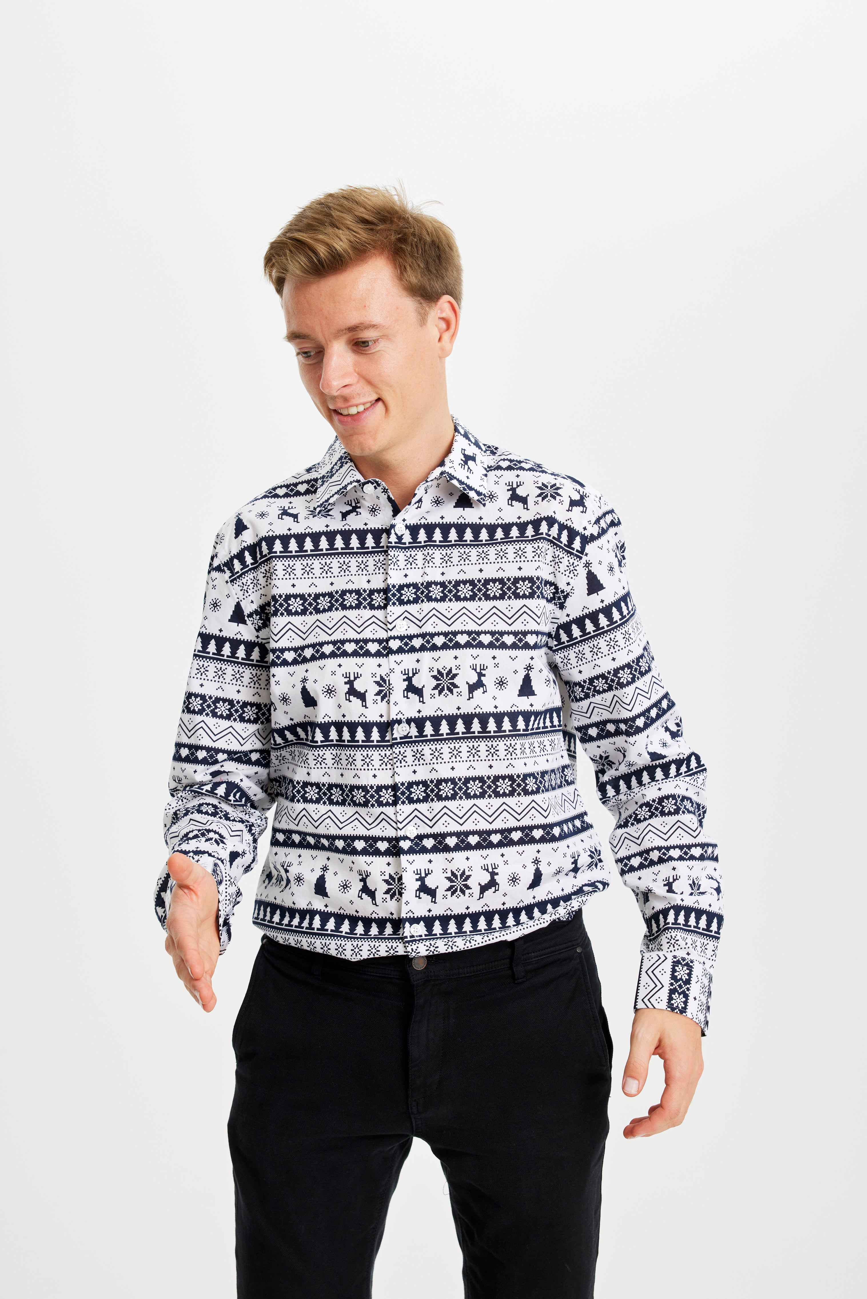 En man skakar hand iklädd en blå och vit jultröja med renar och julgranar på.