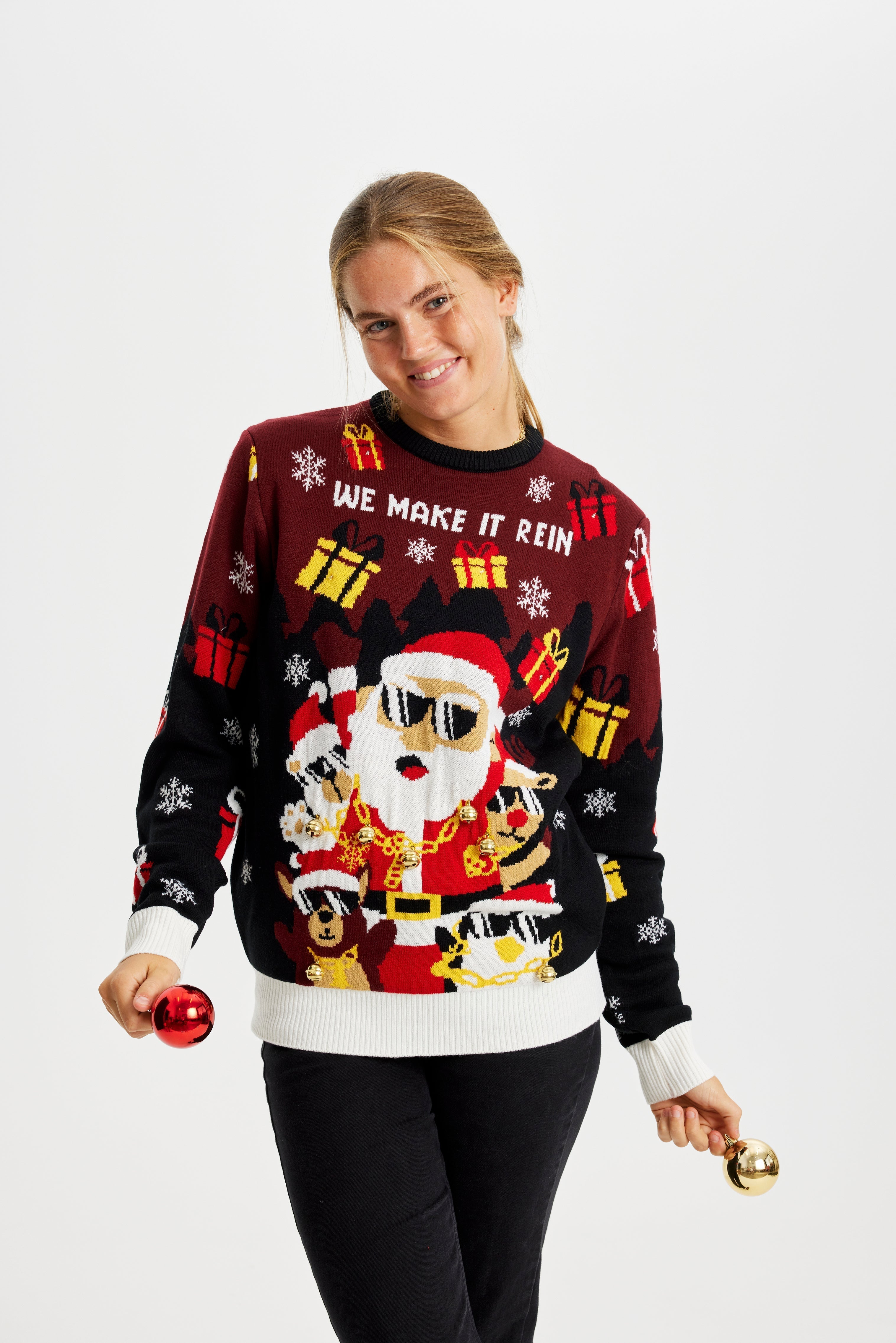 En leende kvinna i röd och svart jultröja med en tomte med solglasögon och tända lampor.