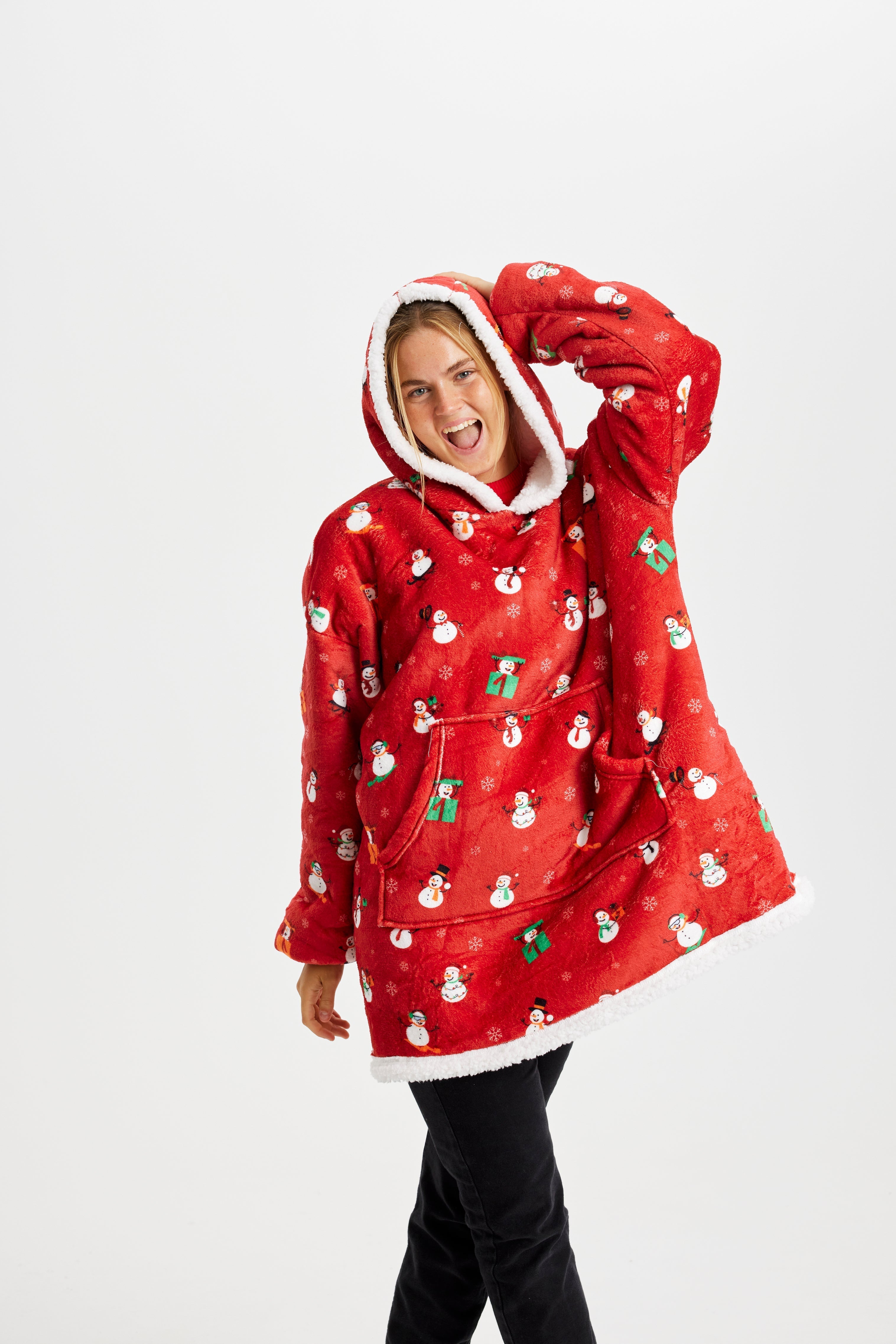 En poserande kvinna i röd julhoodie med snögubbar.