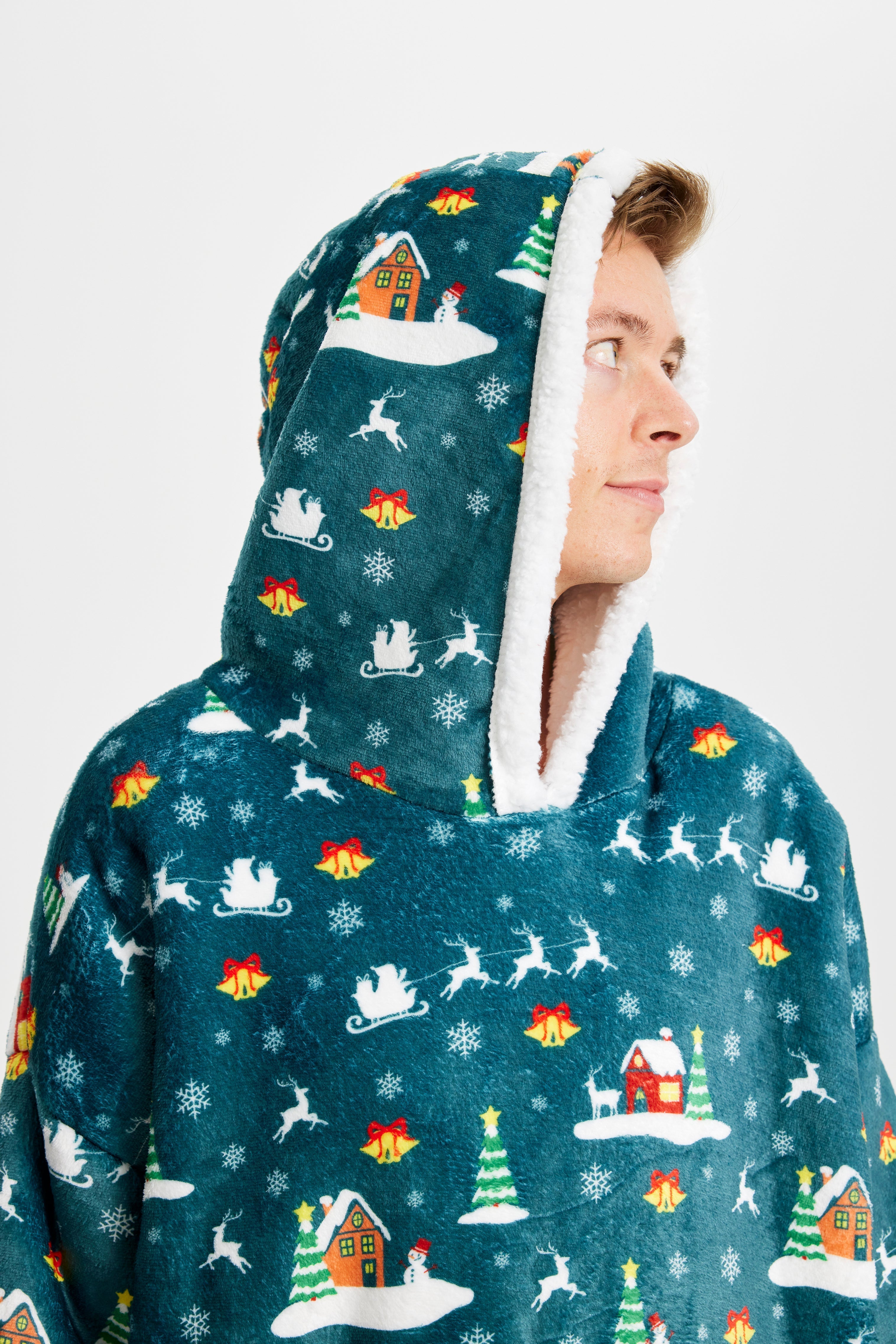 En man som tittar åt sidan iförd en grön huvtröja med snötäckta hus på.