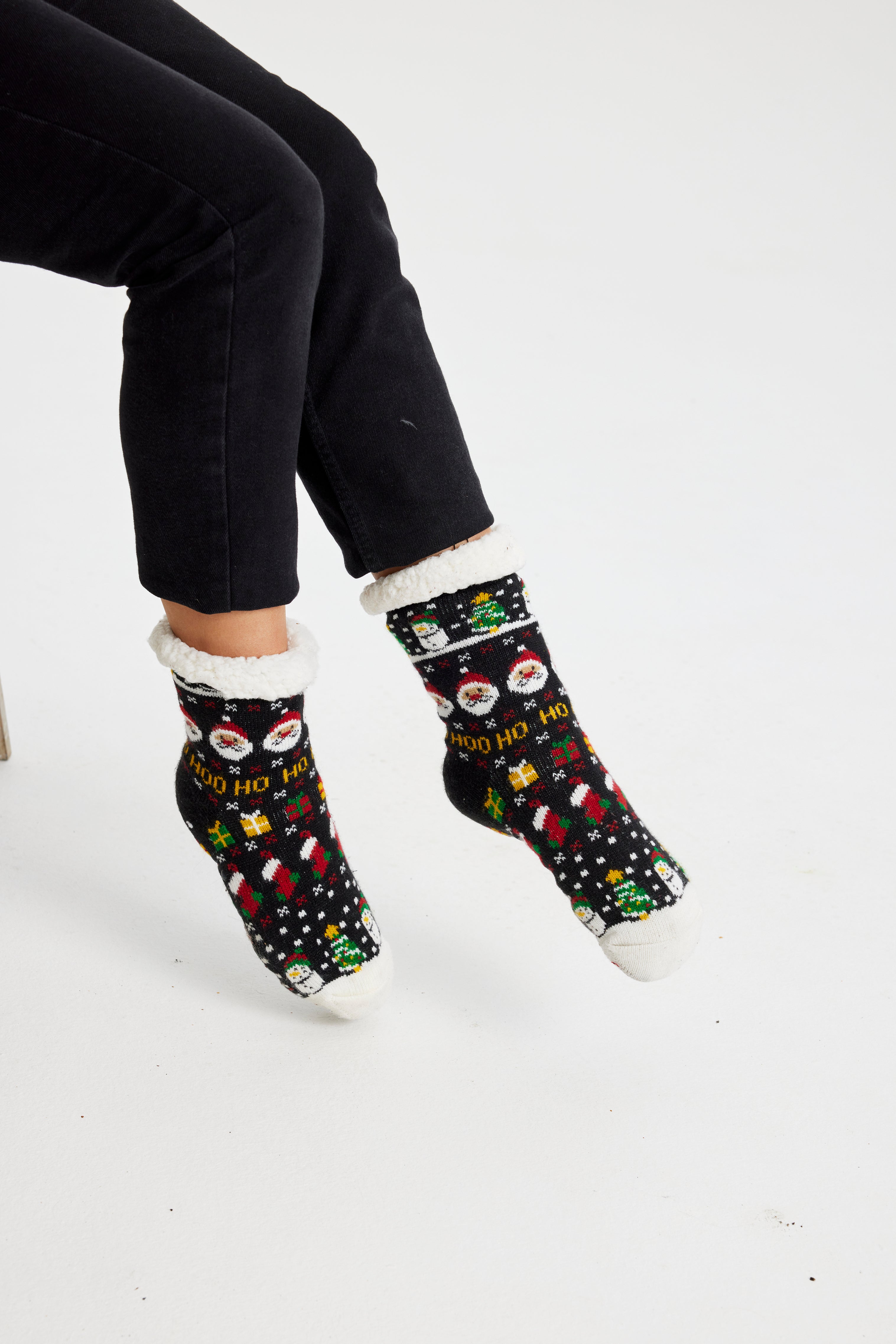 Ett par fötter i svarta julstrumpor med julmönster på.