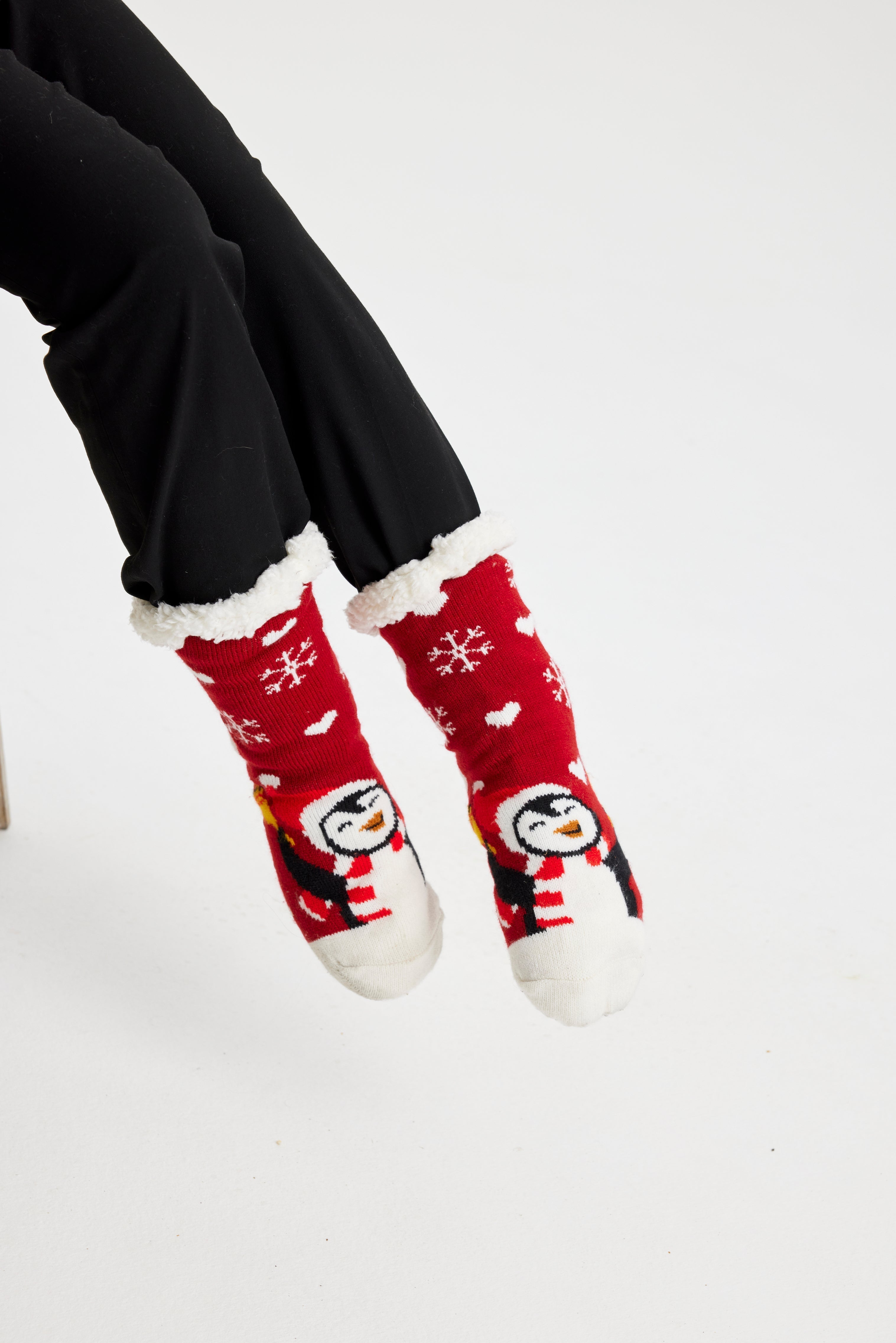 Ett par fötter i röda julstrumpor med pingviner på.