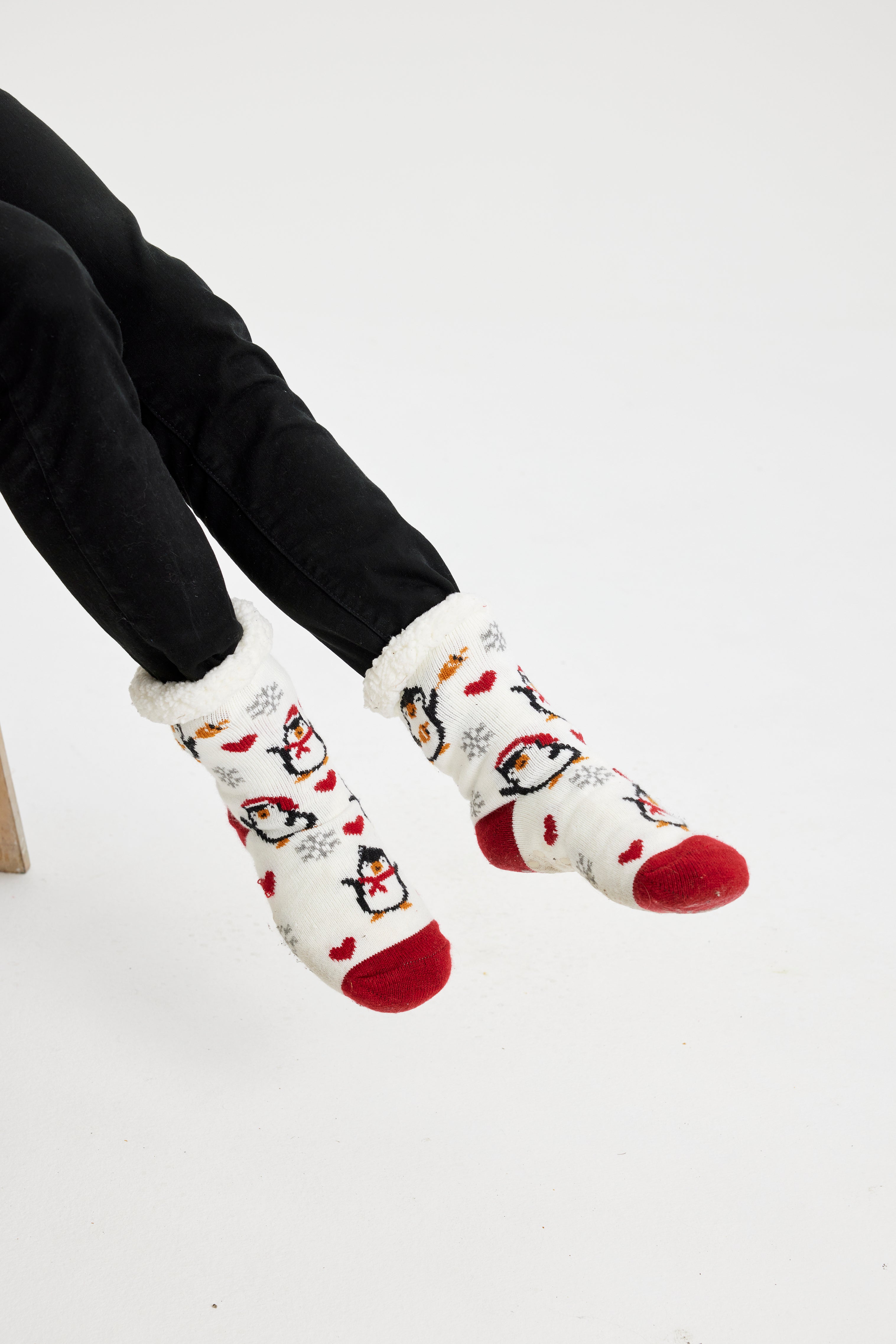 Ett par fötter i vita julstrumpor med pingviner på.