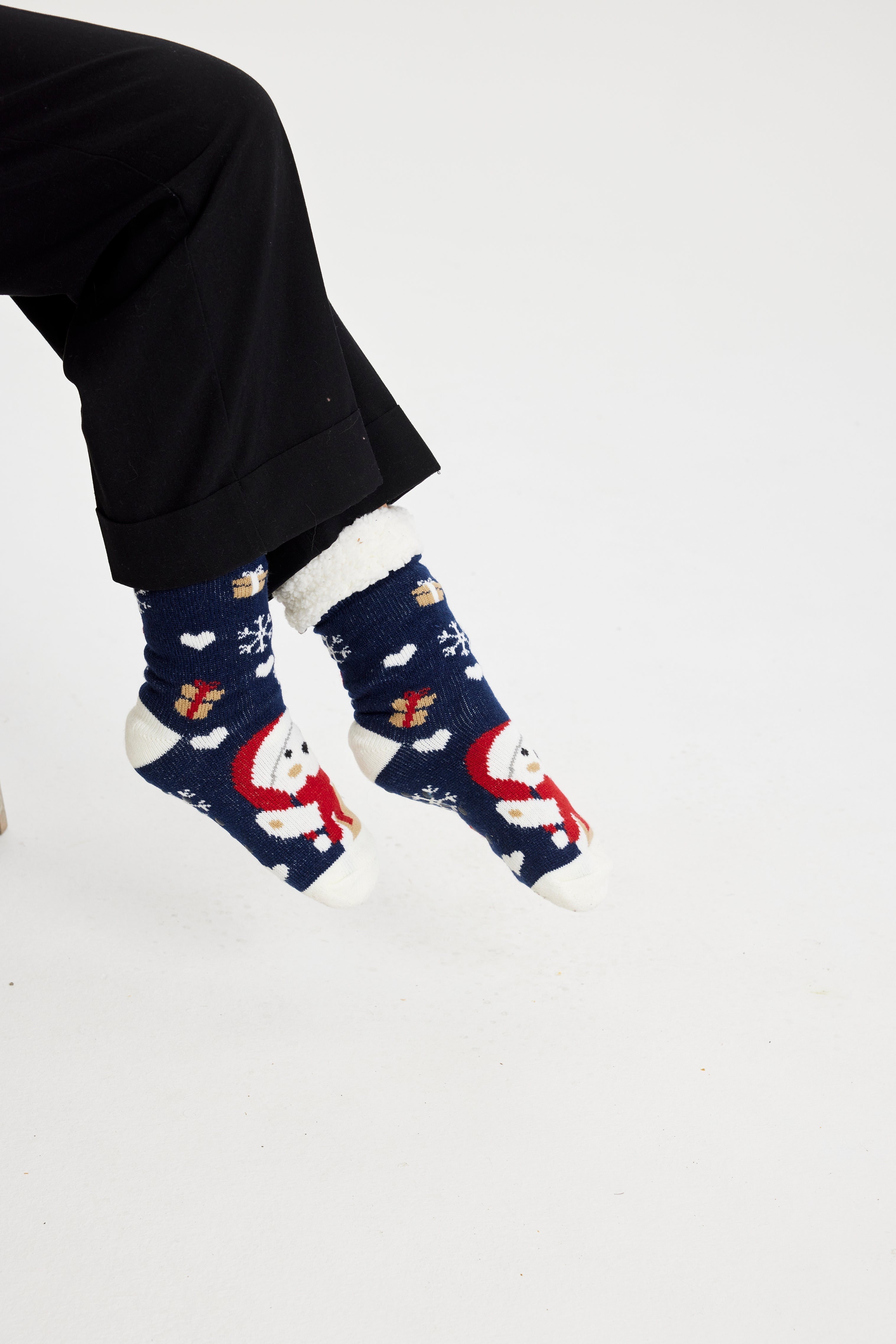 Ett par fötter i blå julstrumpor med jultomten och julklappar på.