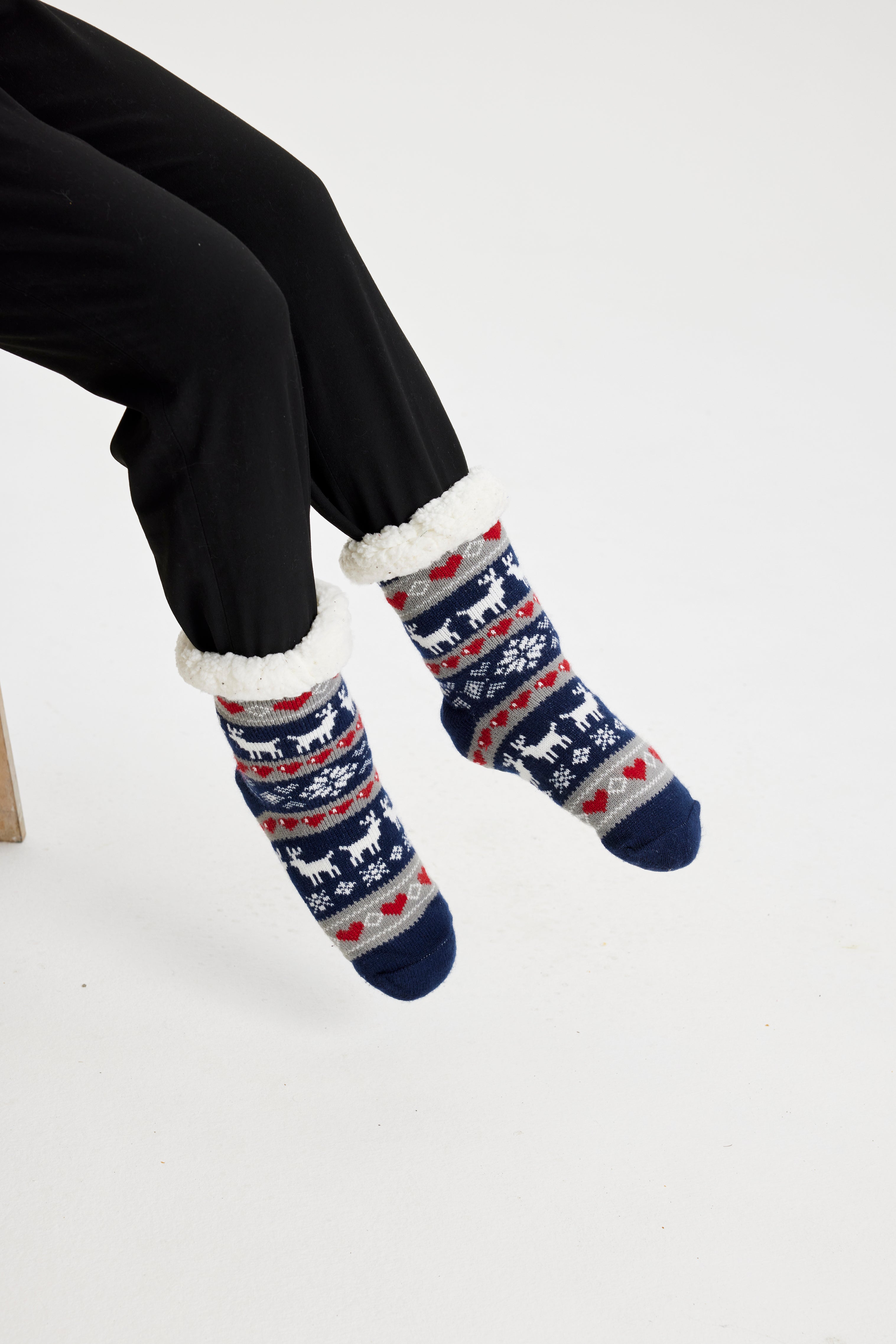 Ett par fötter i blå julstrumpor med julmönster på.