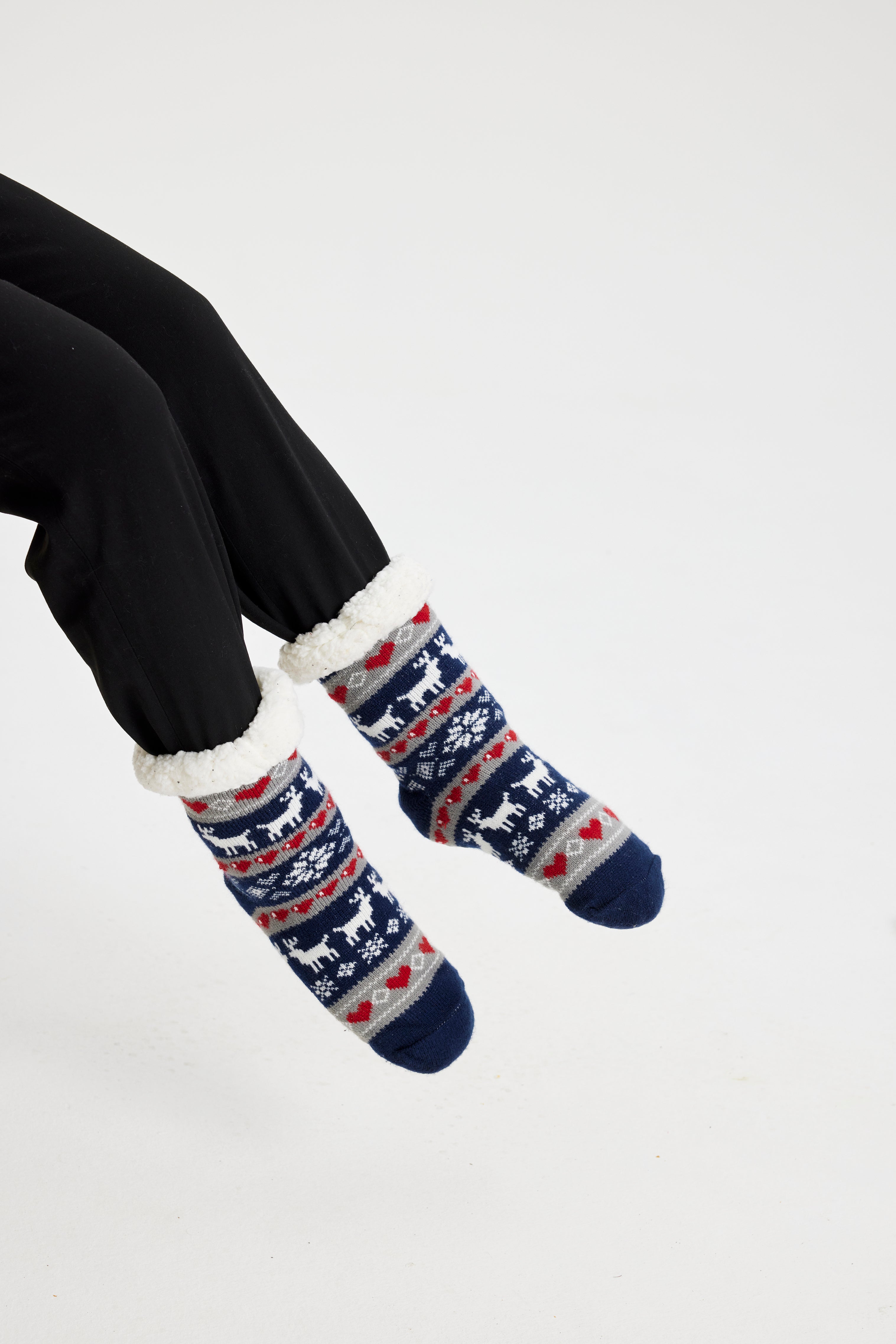 Ett par fötter i blå julstrumpor med julmönster på.