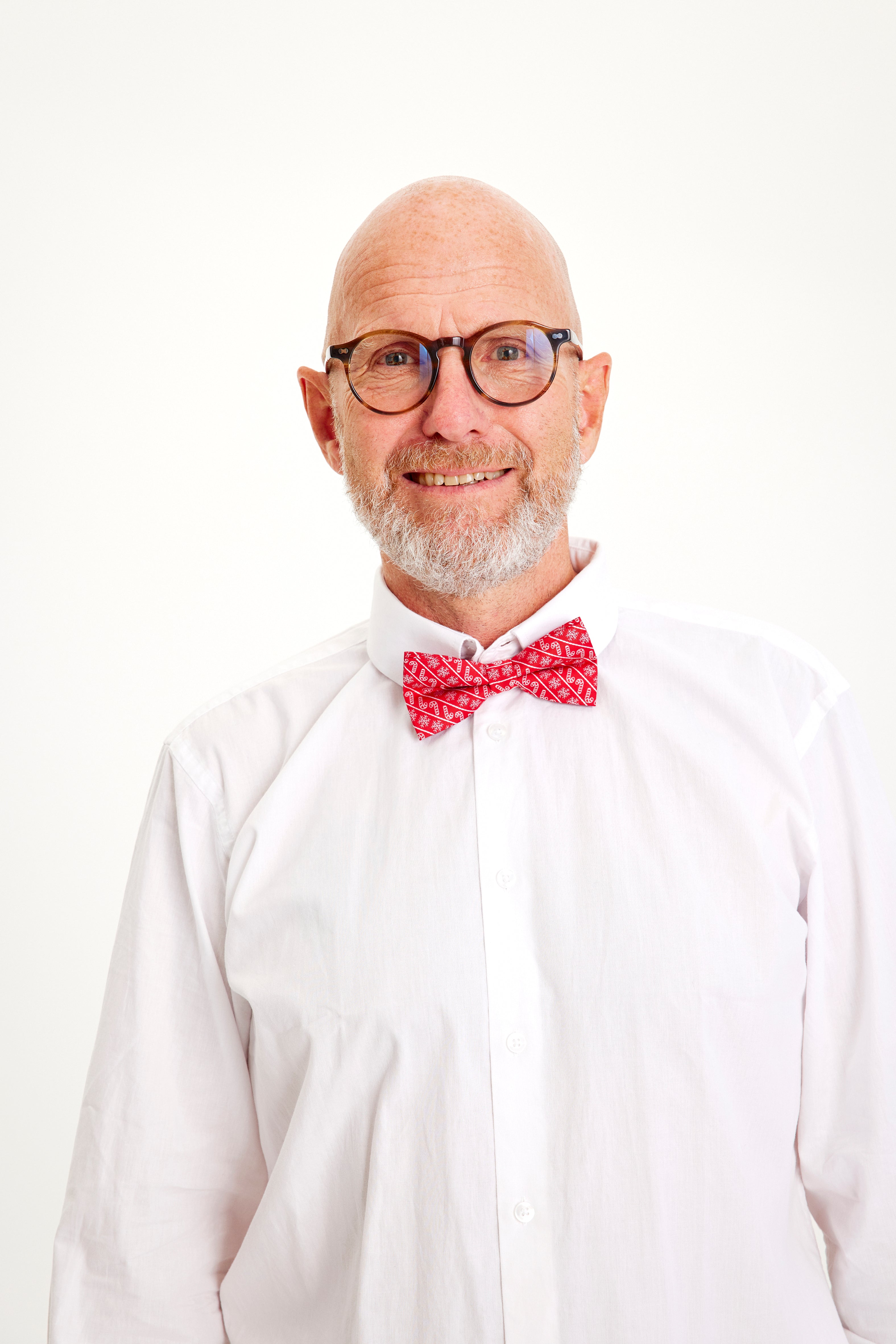 En leende man med vit skjorta och röd fluga.