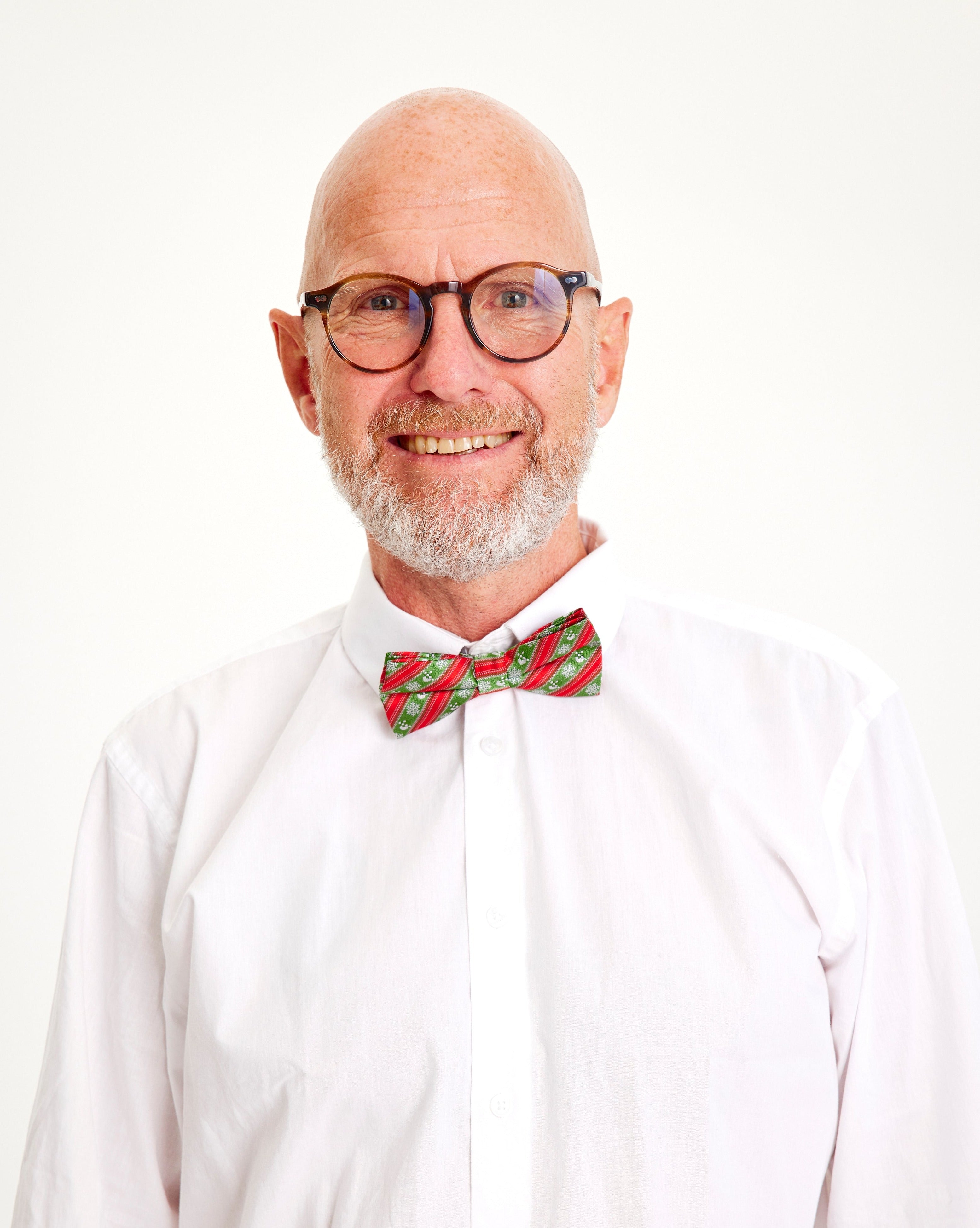 En leende man i vit skjorta och röd och grön fluga.