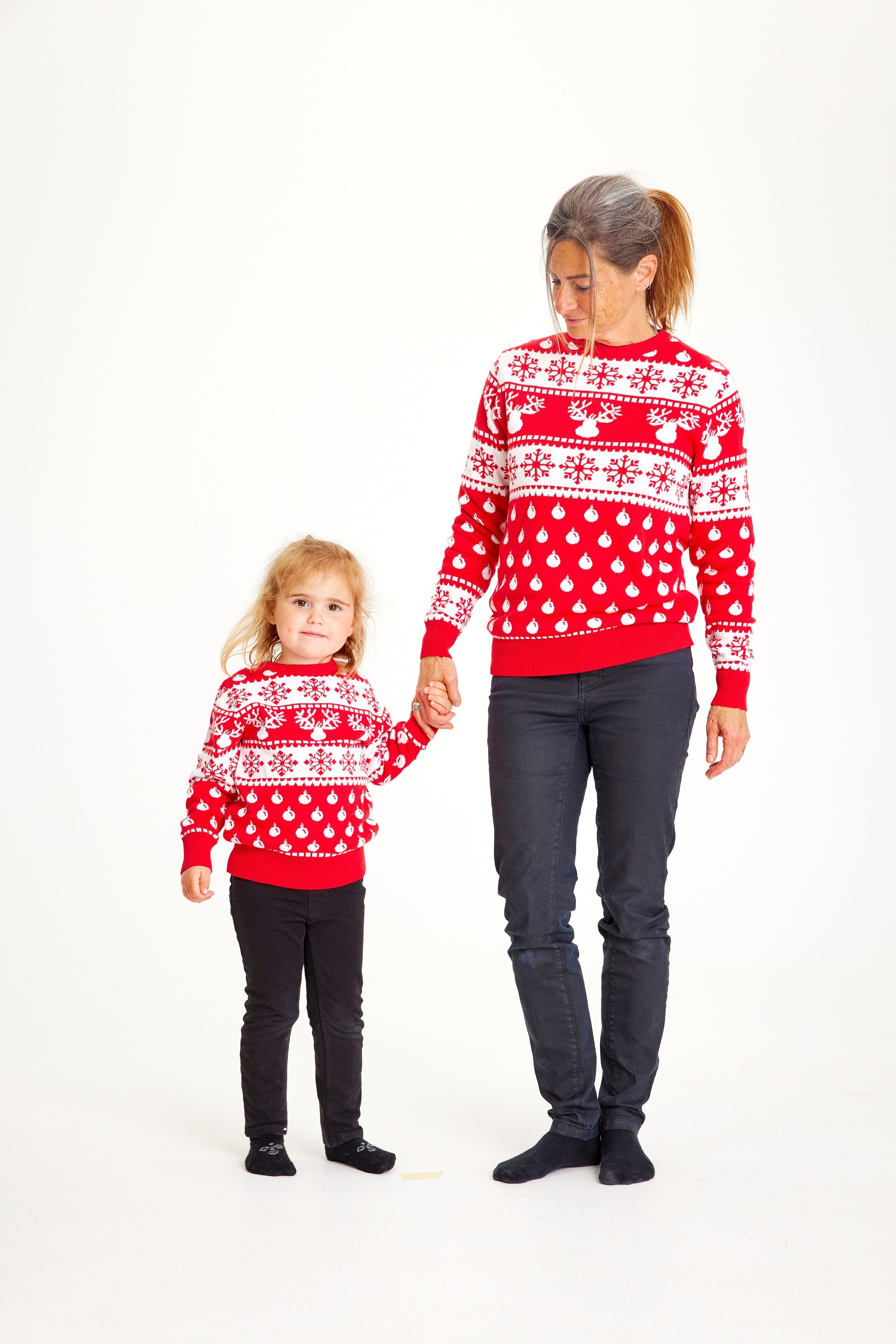 Mamma och barn i röd jultröja med renar, snöflingor och julmönster.